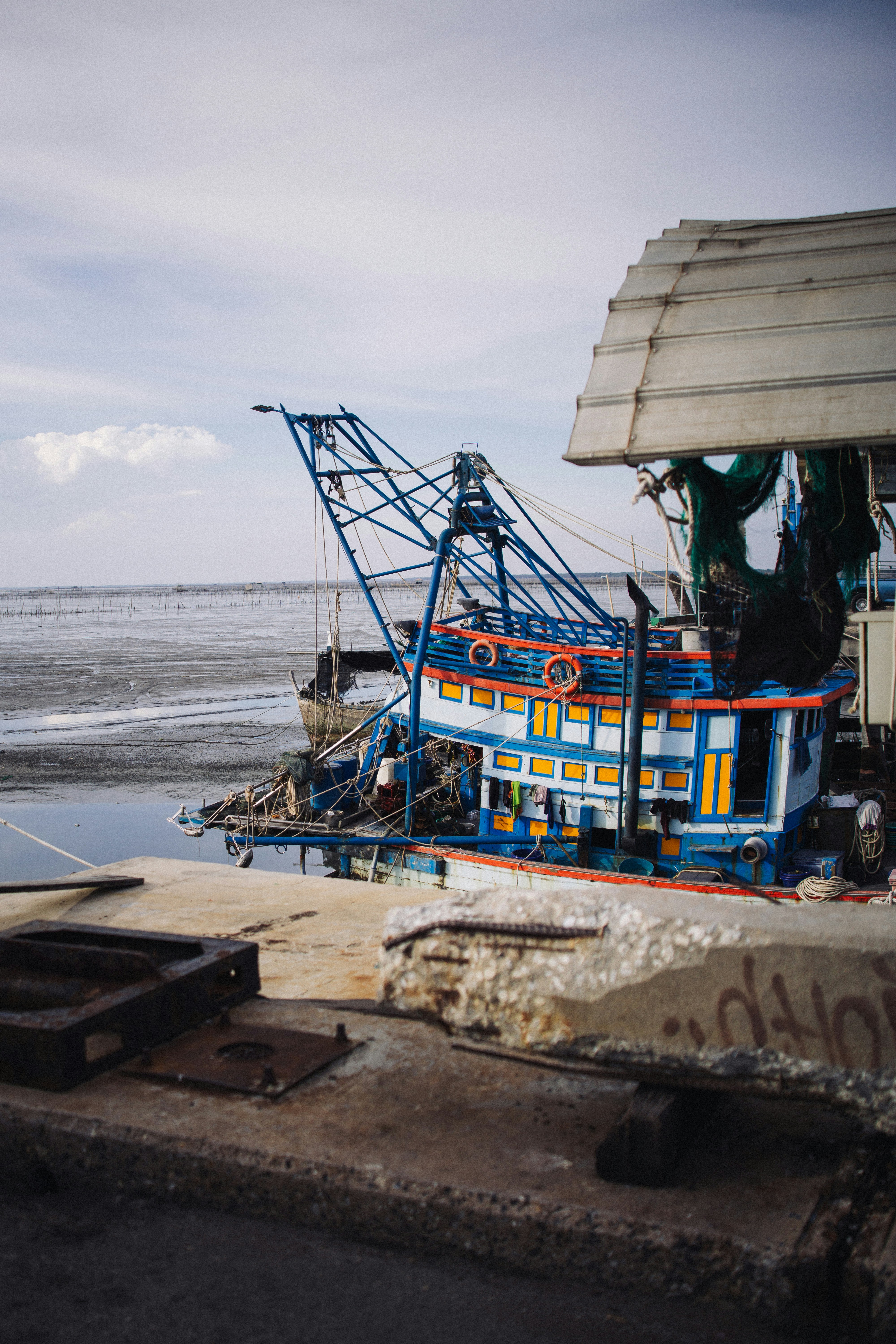A colorful fishing boat docked by a weathered pier.