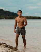 Young man smiling at the beach wearing shorts