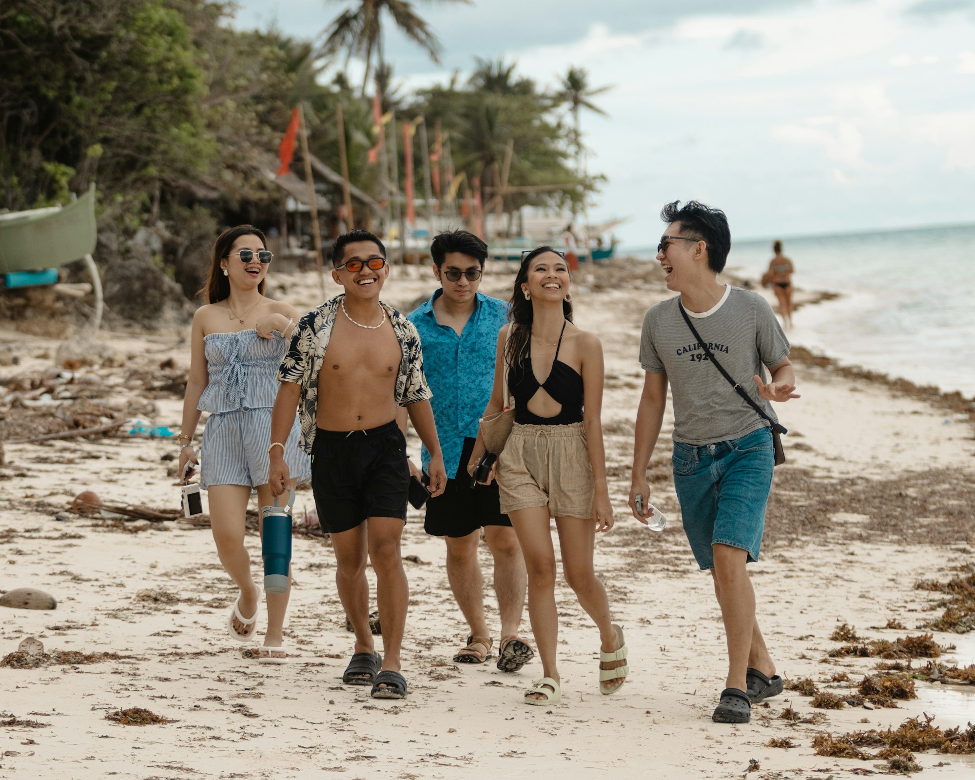 A group of friends walking together on a tropical beach during a summer vacation