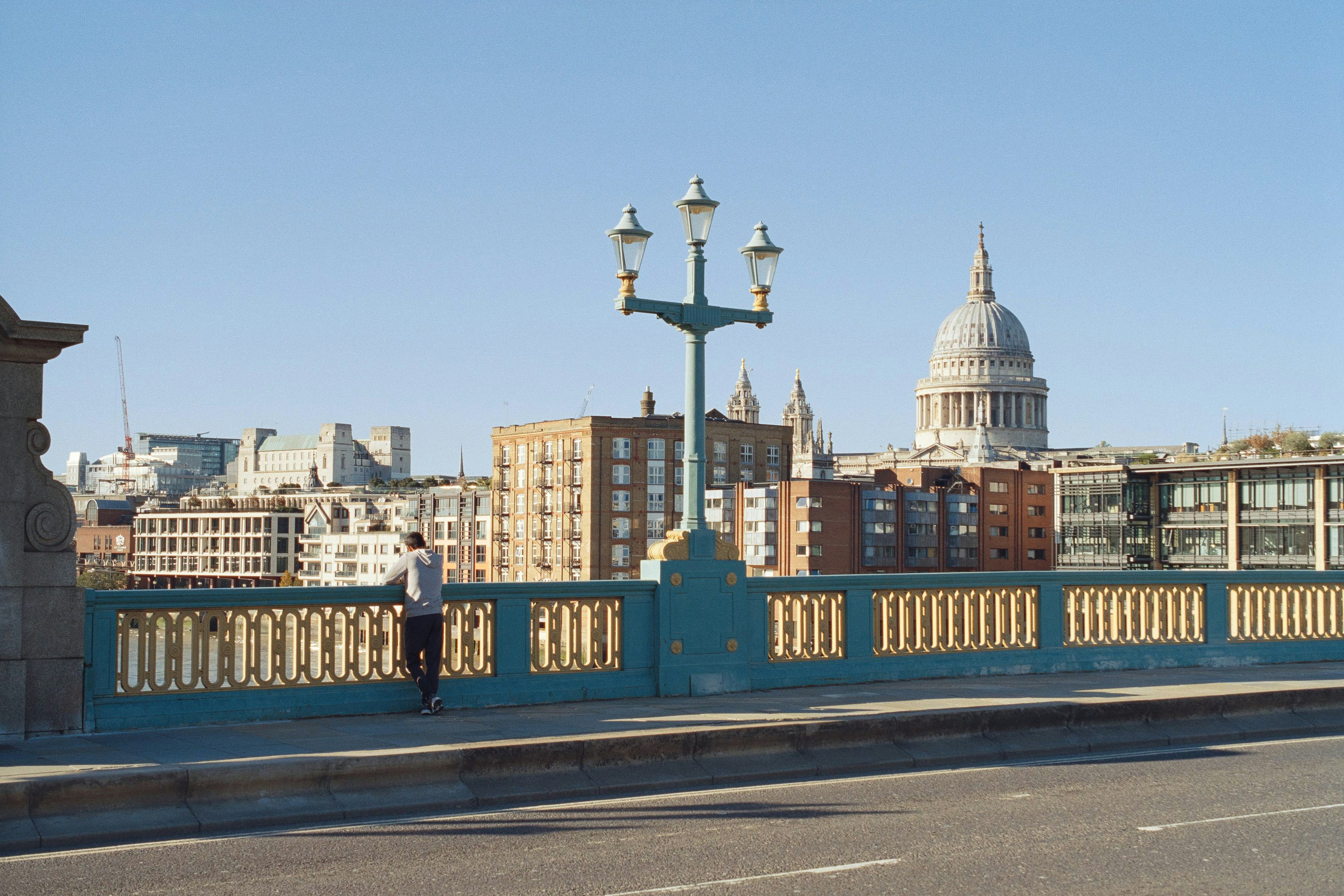 Man standing on bridge overlooking london skyline