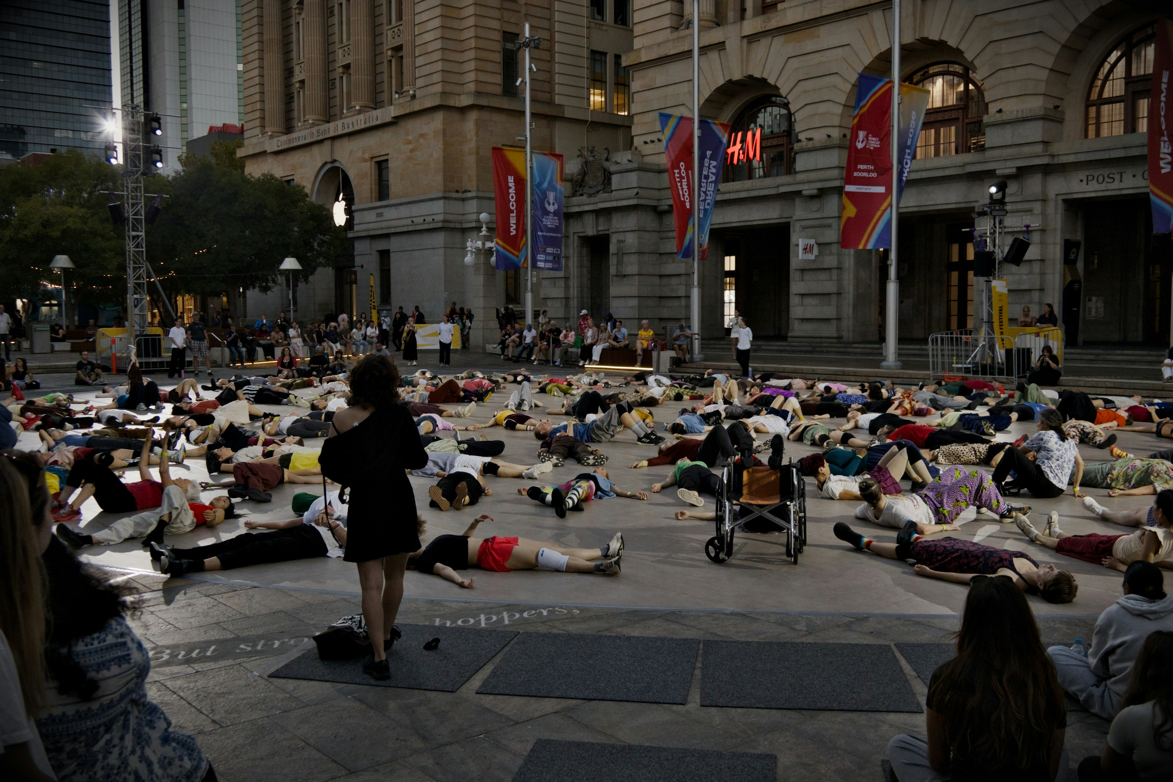 People lying on the ground in a city square.