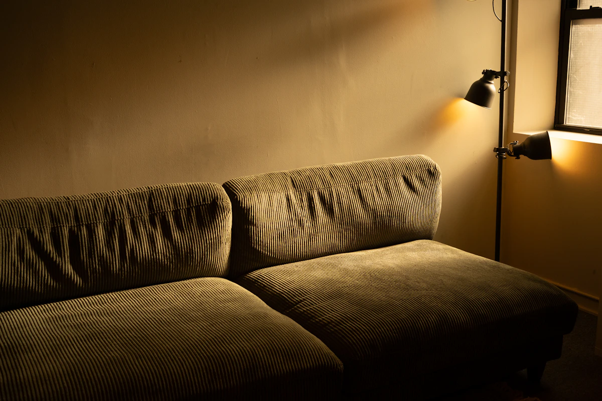 Cozy living room featuring a sofa, floor lamp and warm layered interior lighting