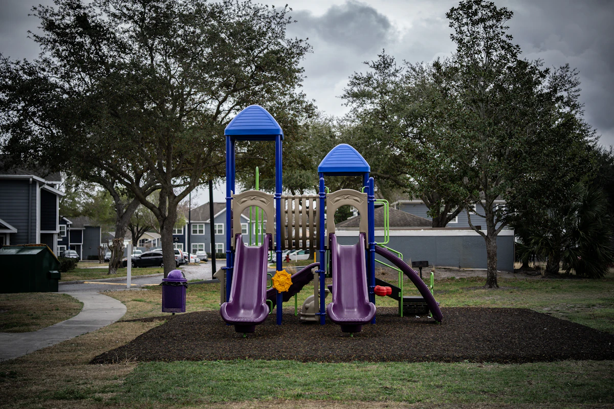A colorful playground with two slides and trees