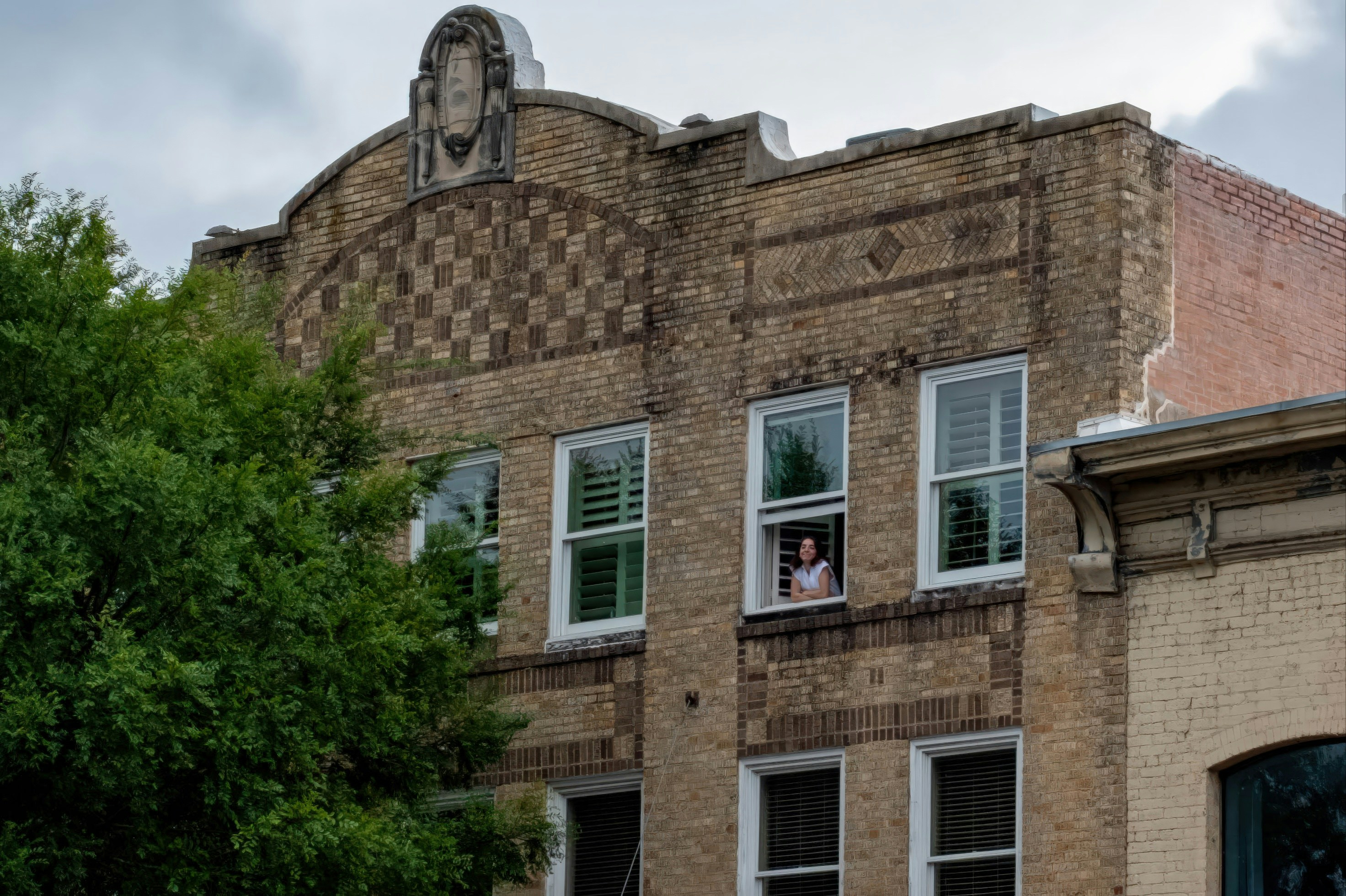 Person looking out a window of a brick building.