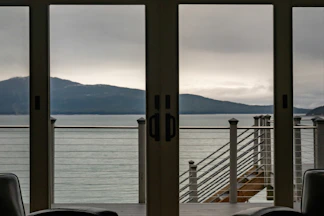 View of a calm sea and mountains through glass doors.