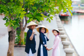 Three people in conical hats by a canal