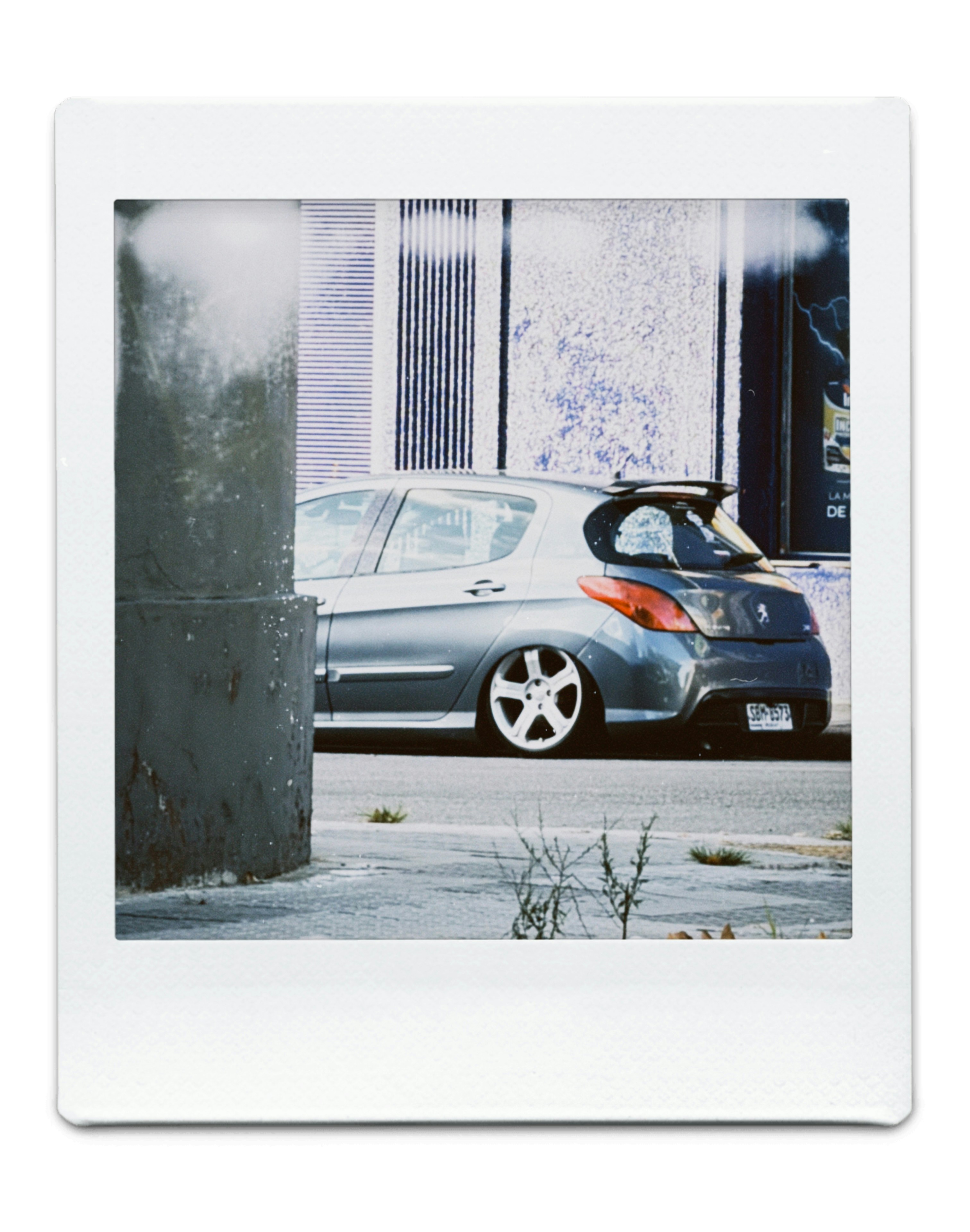 Silver car with custom wheels parked on street
