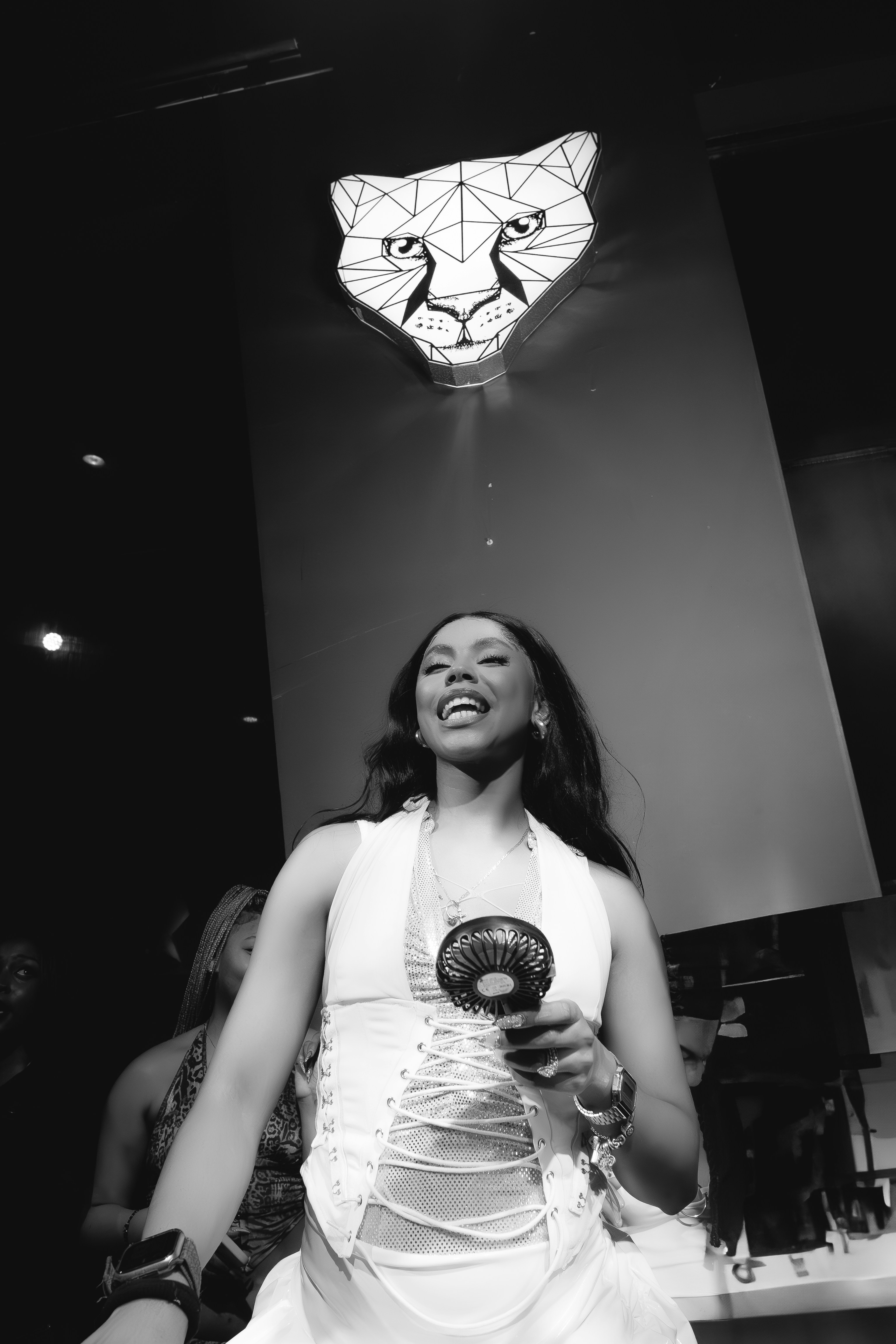 Wanita memegang kipas angin dengan logo cheetah di belakangnya