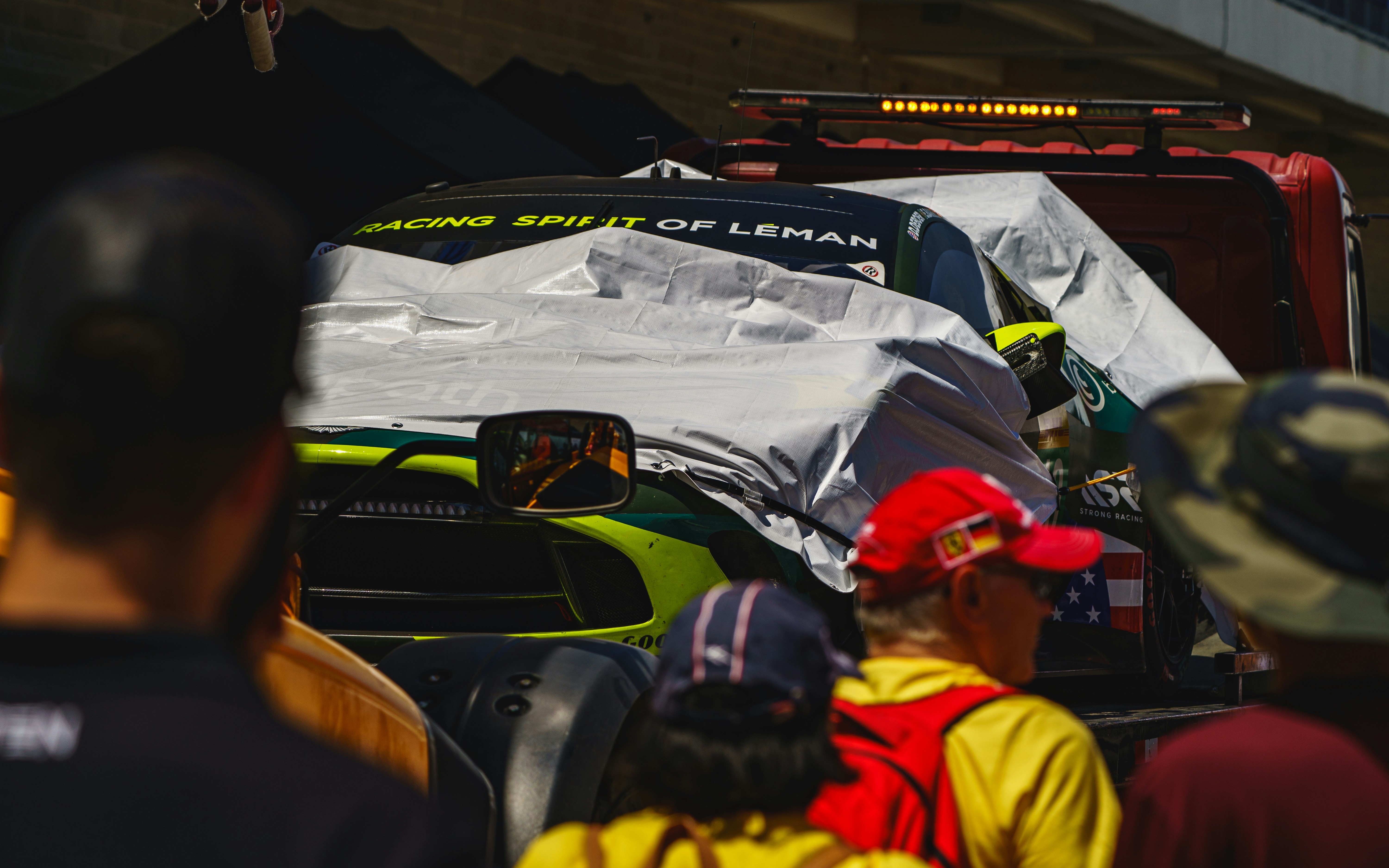 Race car covered with a tarp on a tow truck.