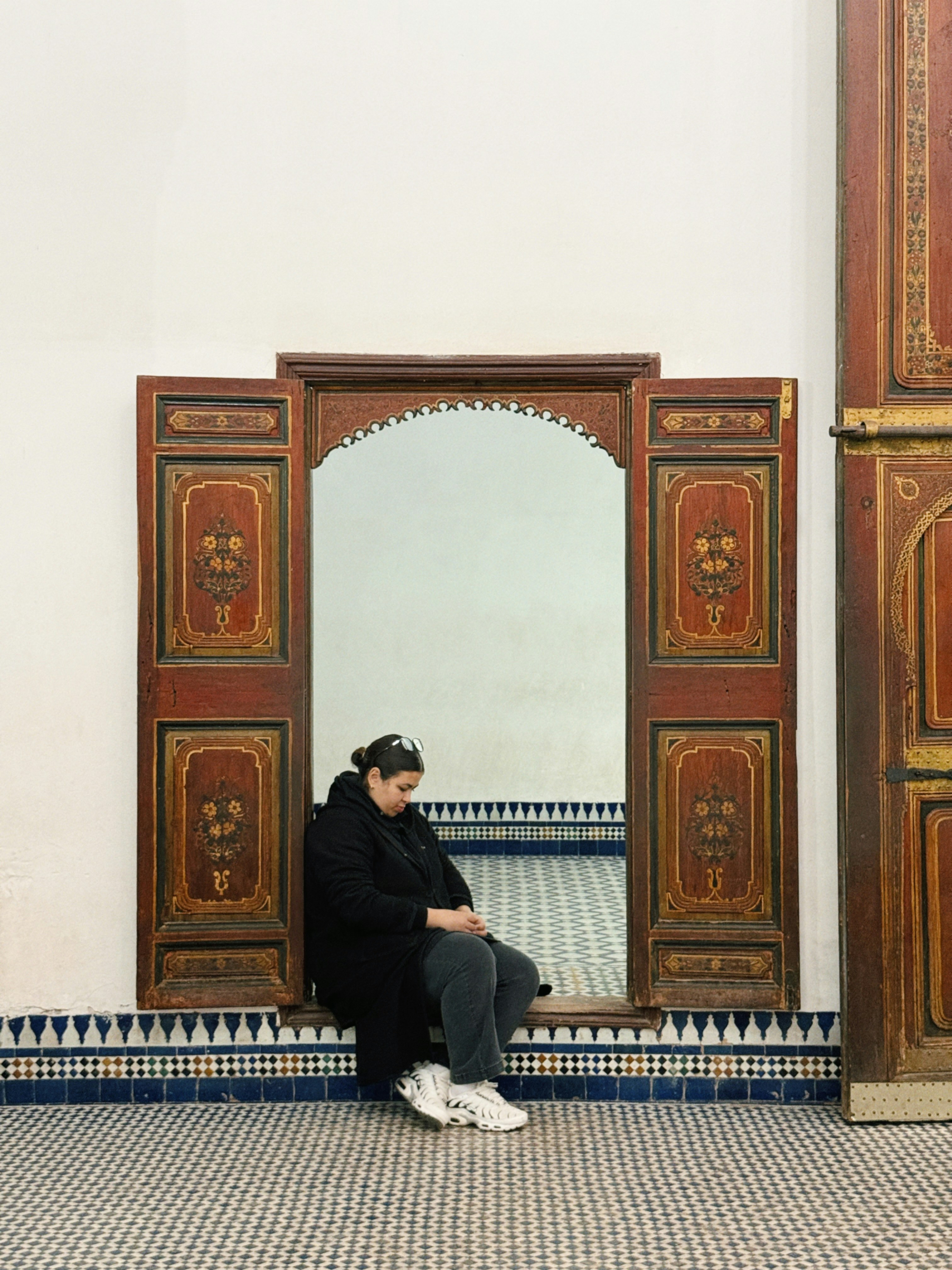 Woman sitting in ornate doorway with mirror