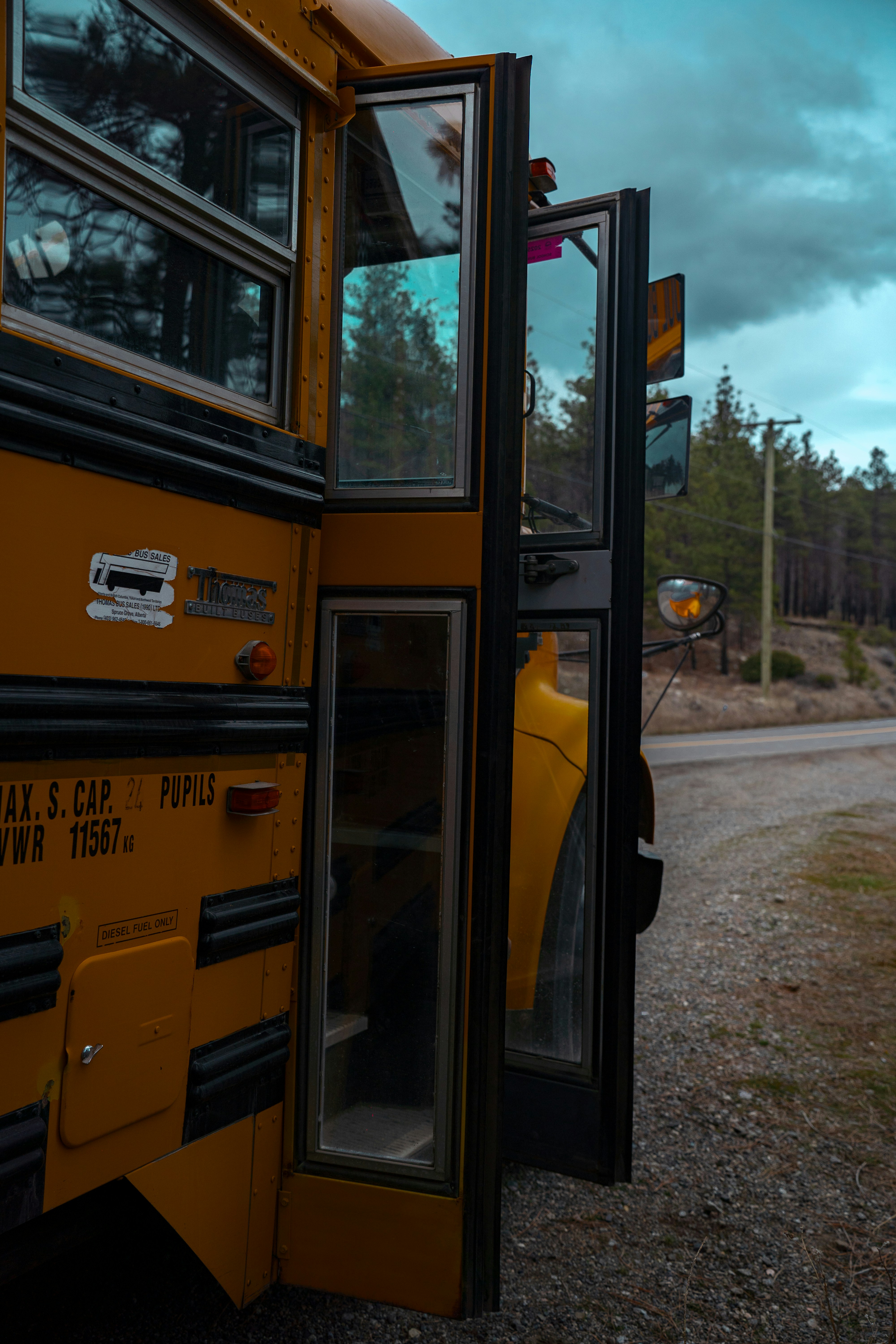 Ônibus escolar amarelo com portas abertas na estrada.