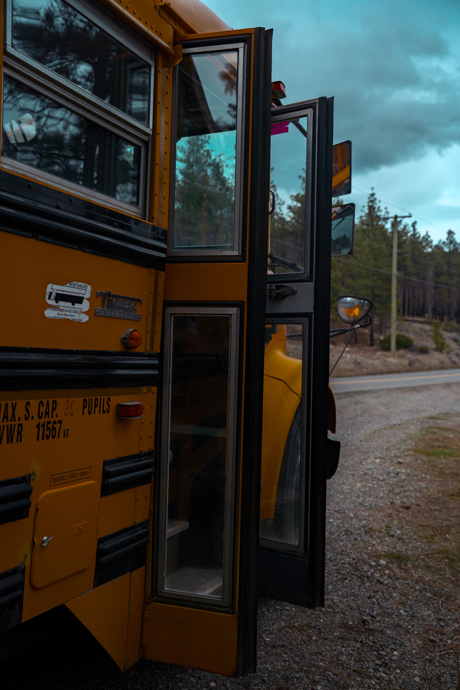 A yellow school bus with its doors open on a quiet road