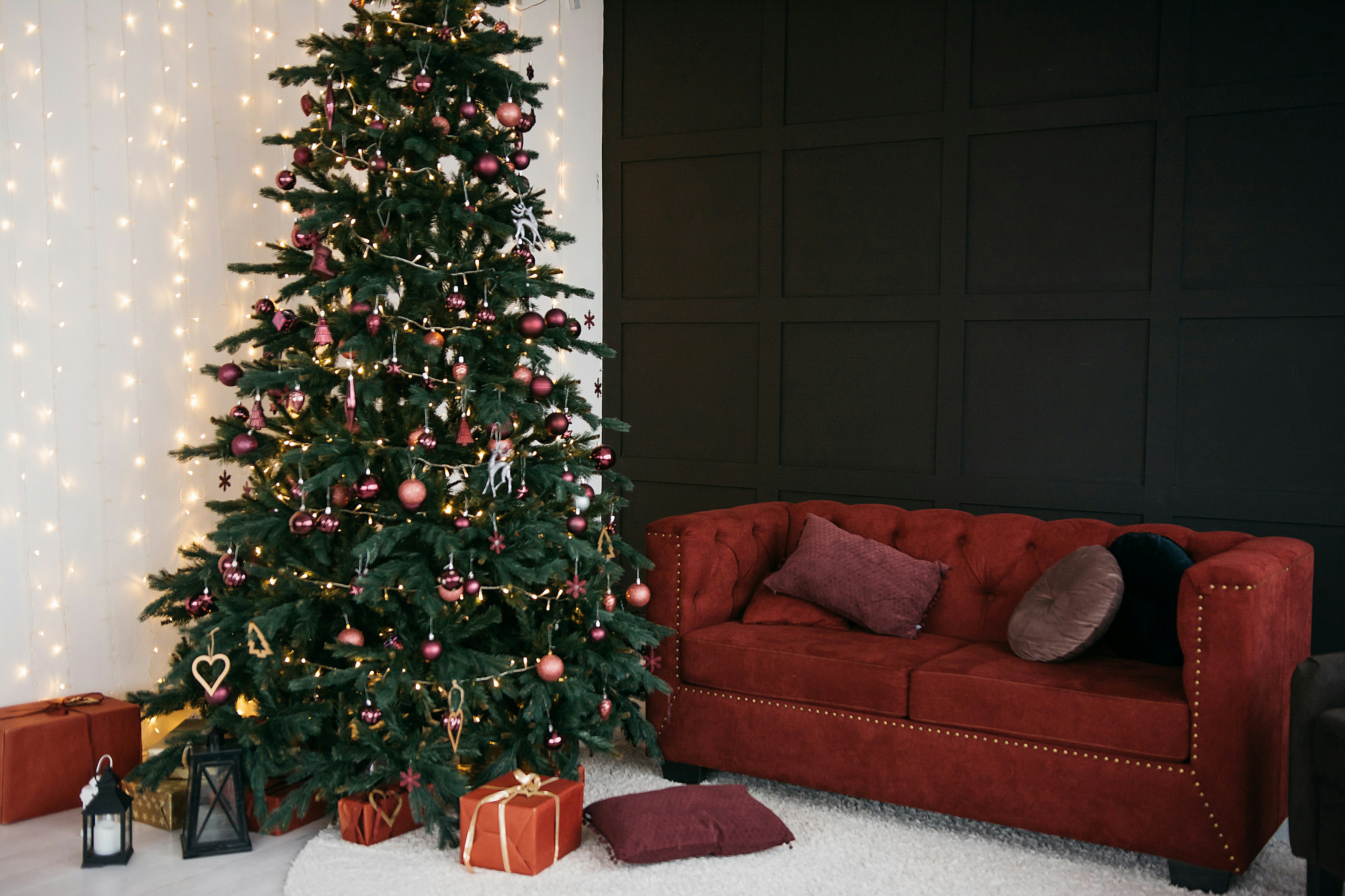 Decorated christmas tree with gifts and red sofa