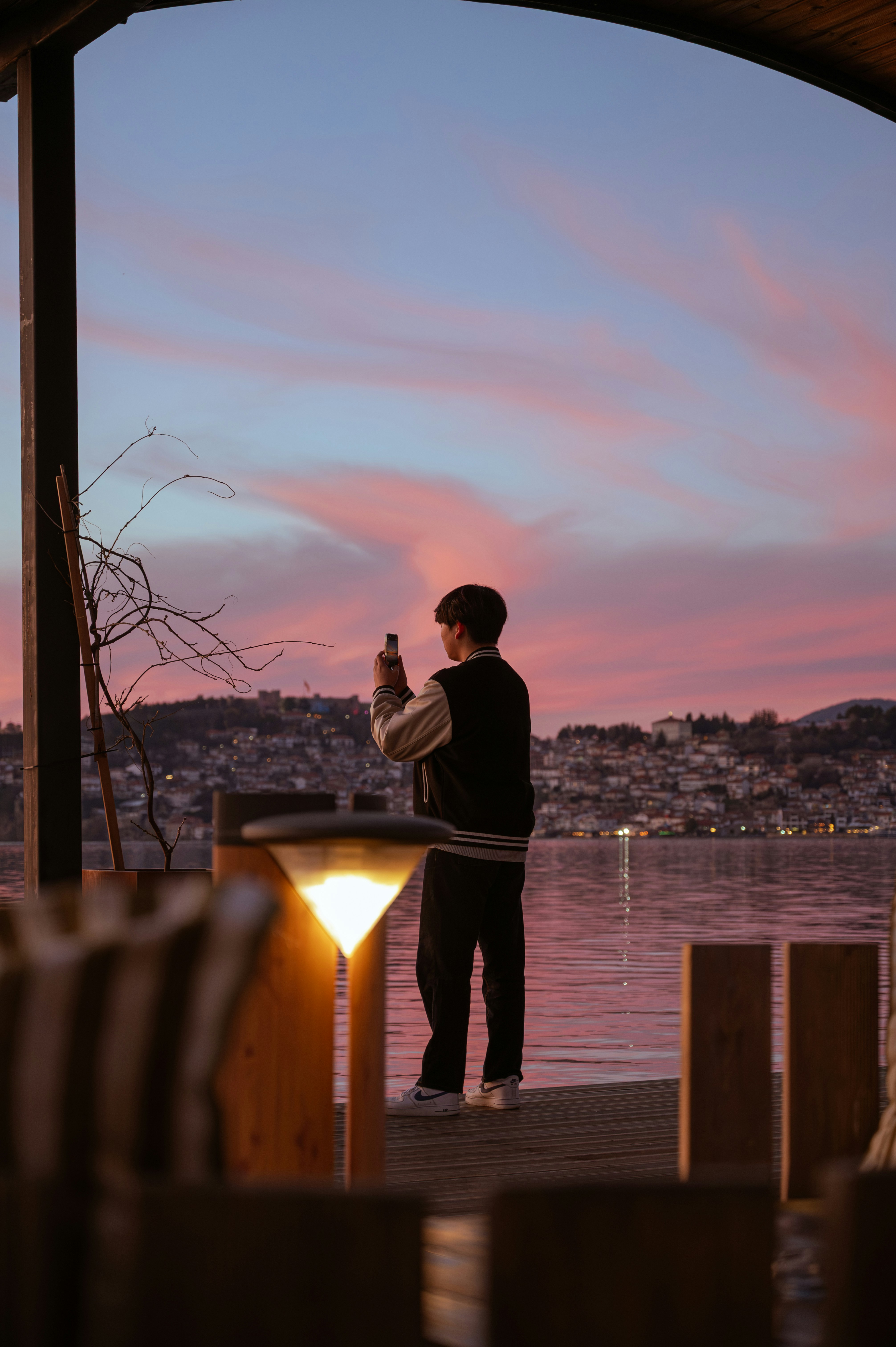 Person photographing a pastel sunset over the water.