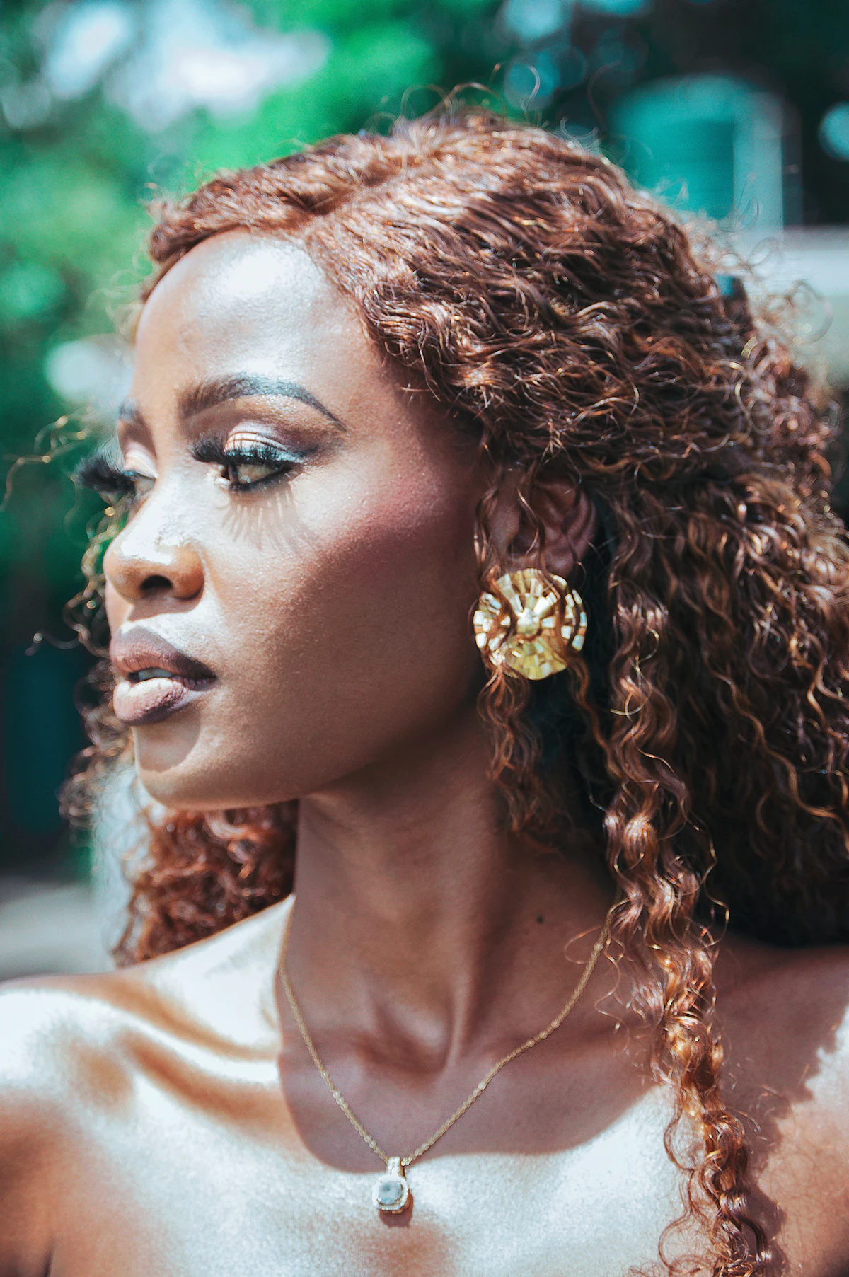 Portrait d'une femme aux cheveux bouclés portant une boucle d'oreille dorée