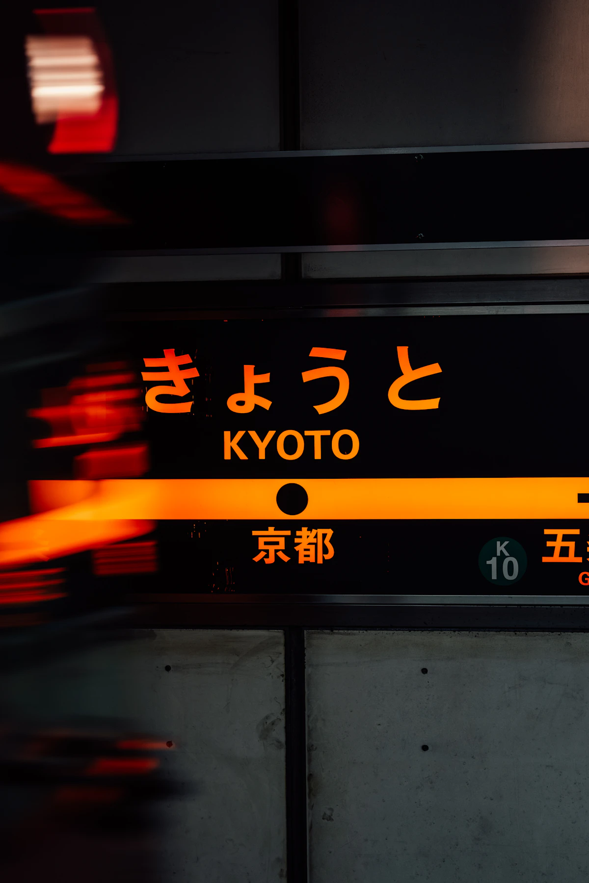 The Kyoto Station platform sign with a train passing