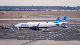 Jetblue airplane parked at airport tarmac with service vehicles