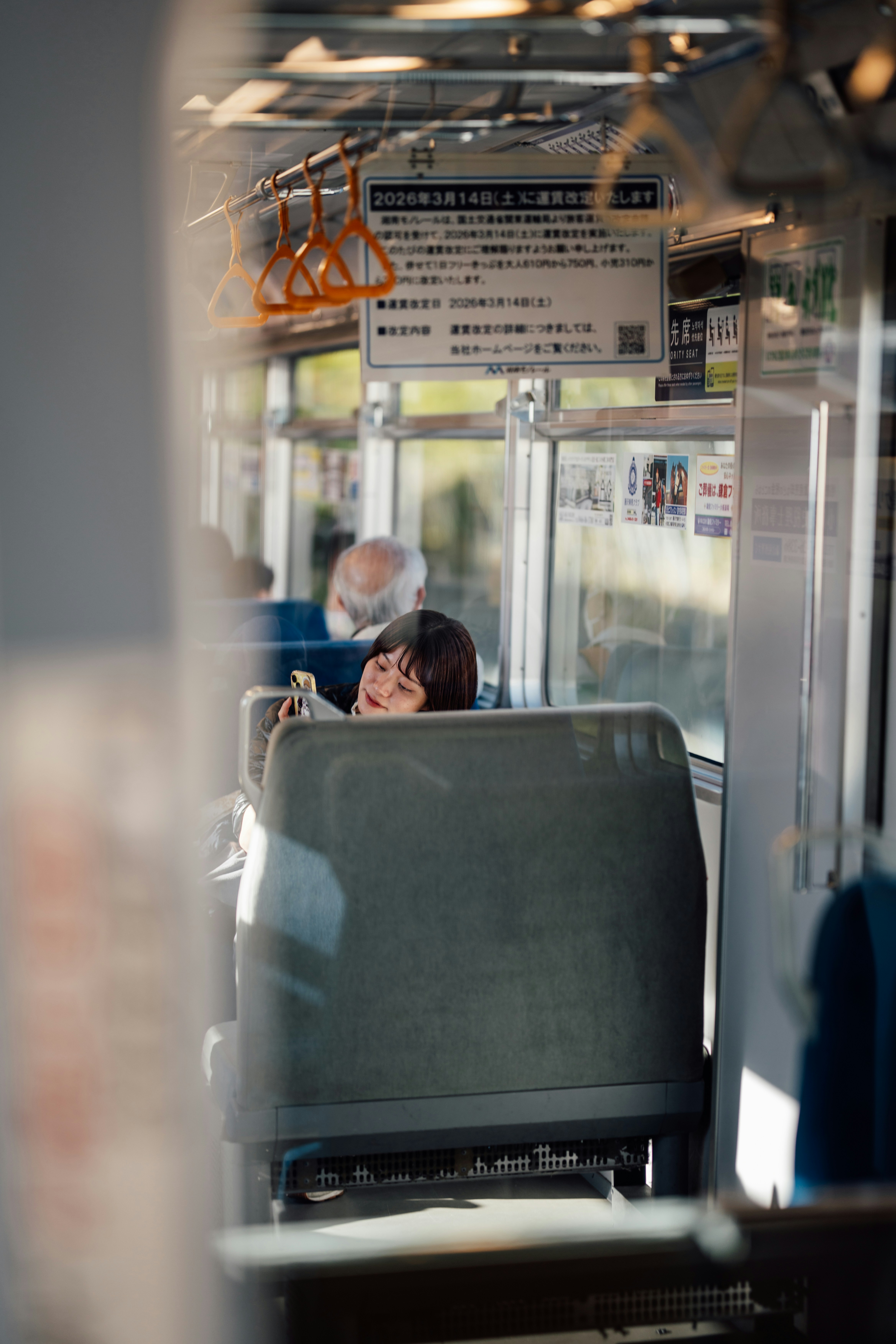 Frau schläft in einem Zug und schaut auf ihr Handy.