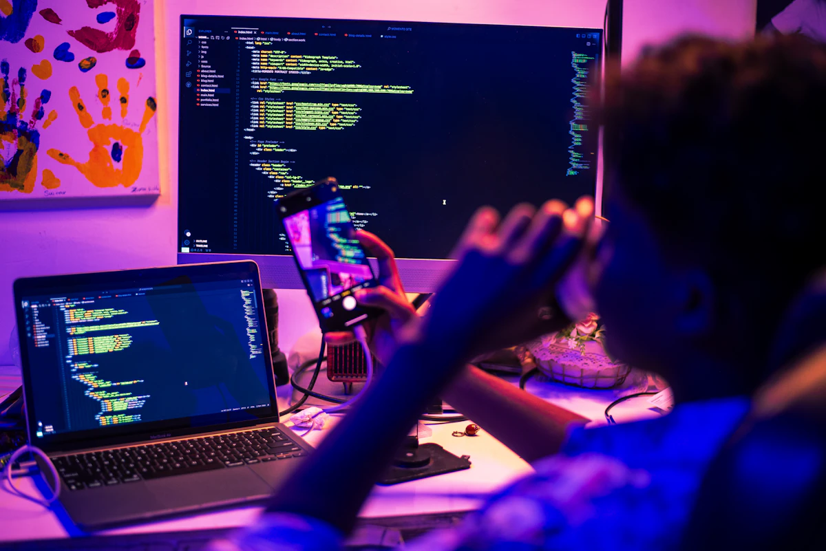 Person coding on multiple screens at night.