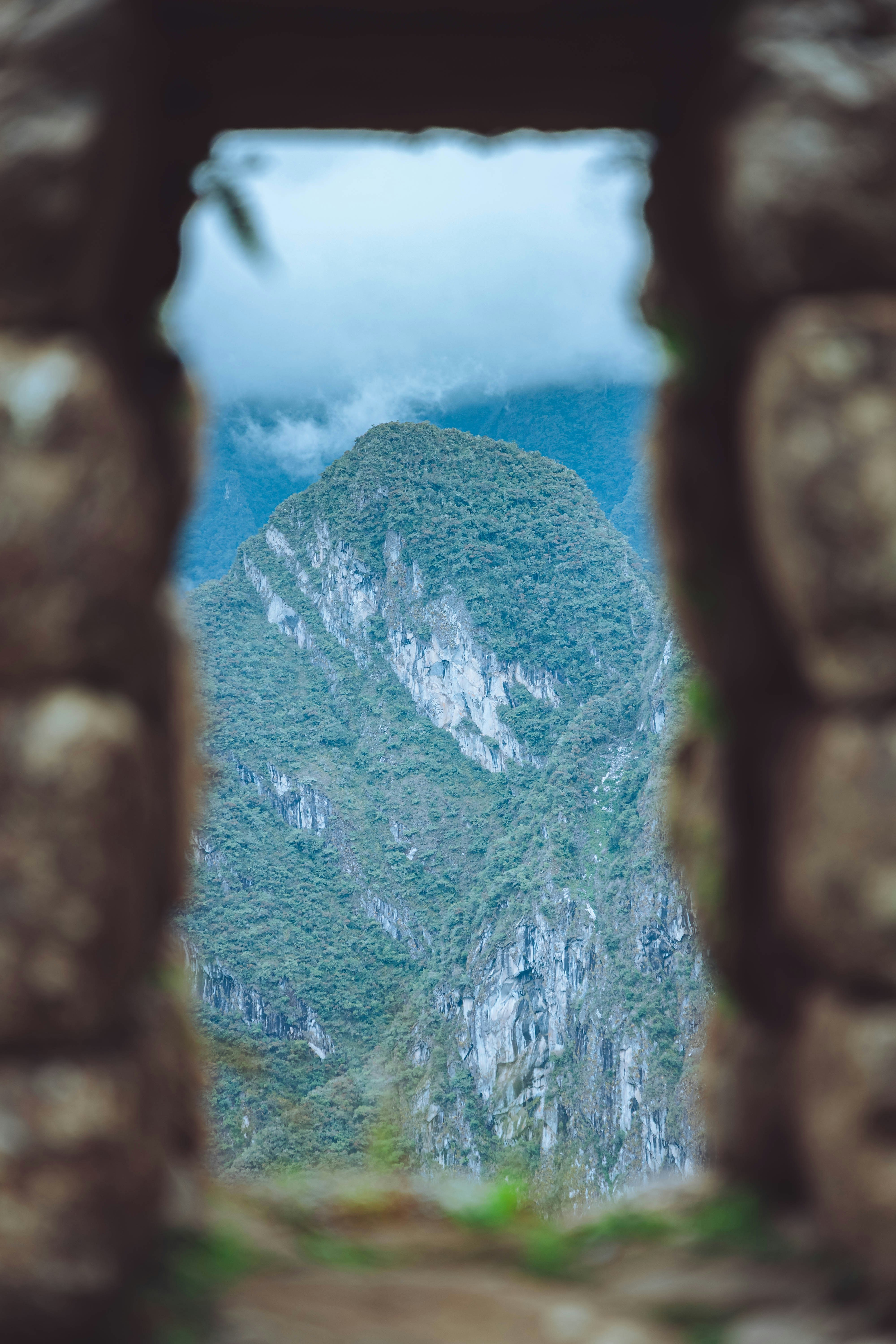 Steinbogen, der einen üppigen, nebelverhangenen Berggipfel einrahmt
