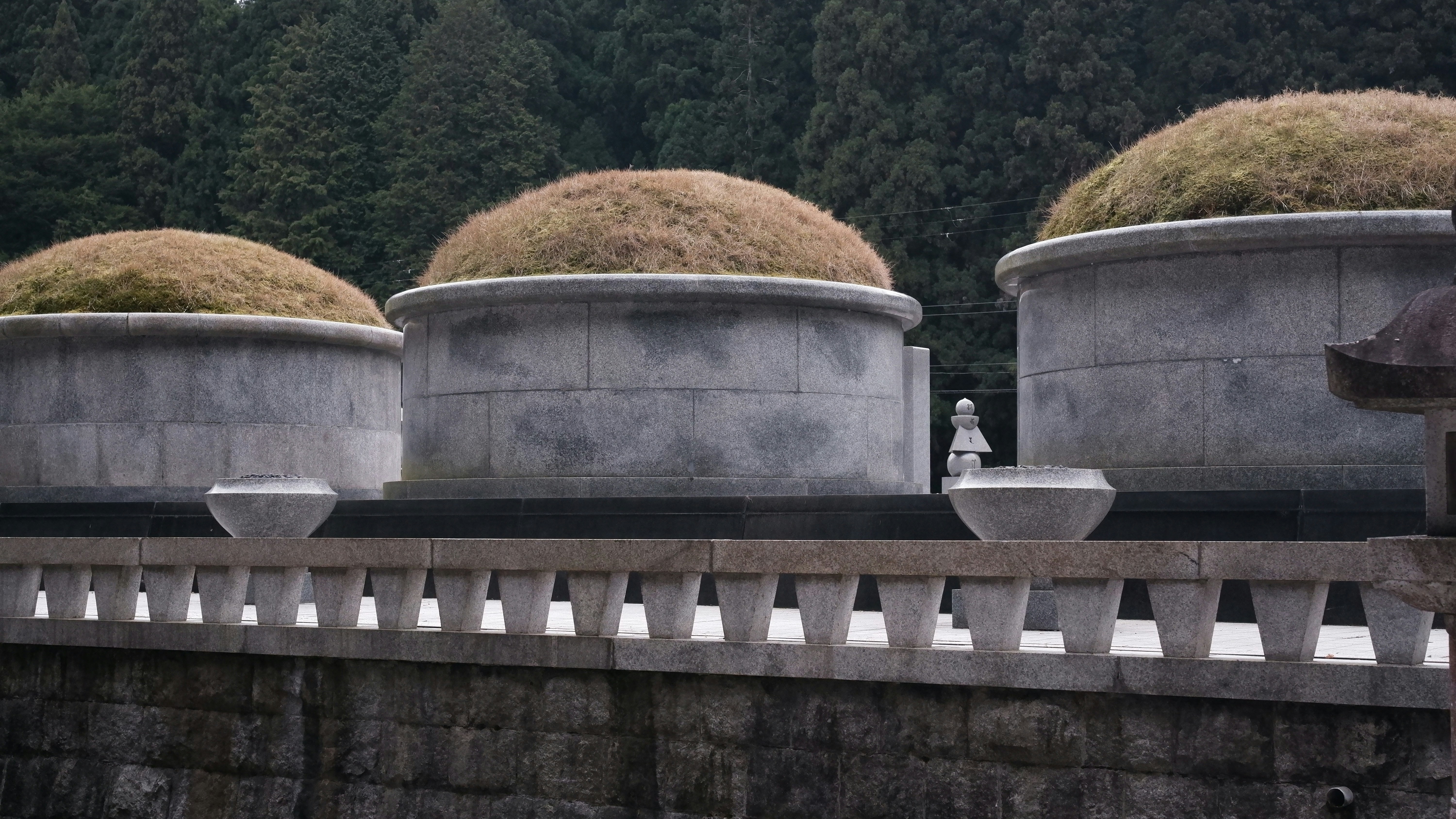 Three ancient tombs topped with grass and stone bases.