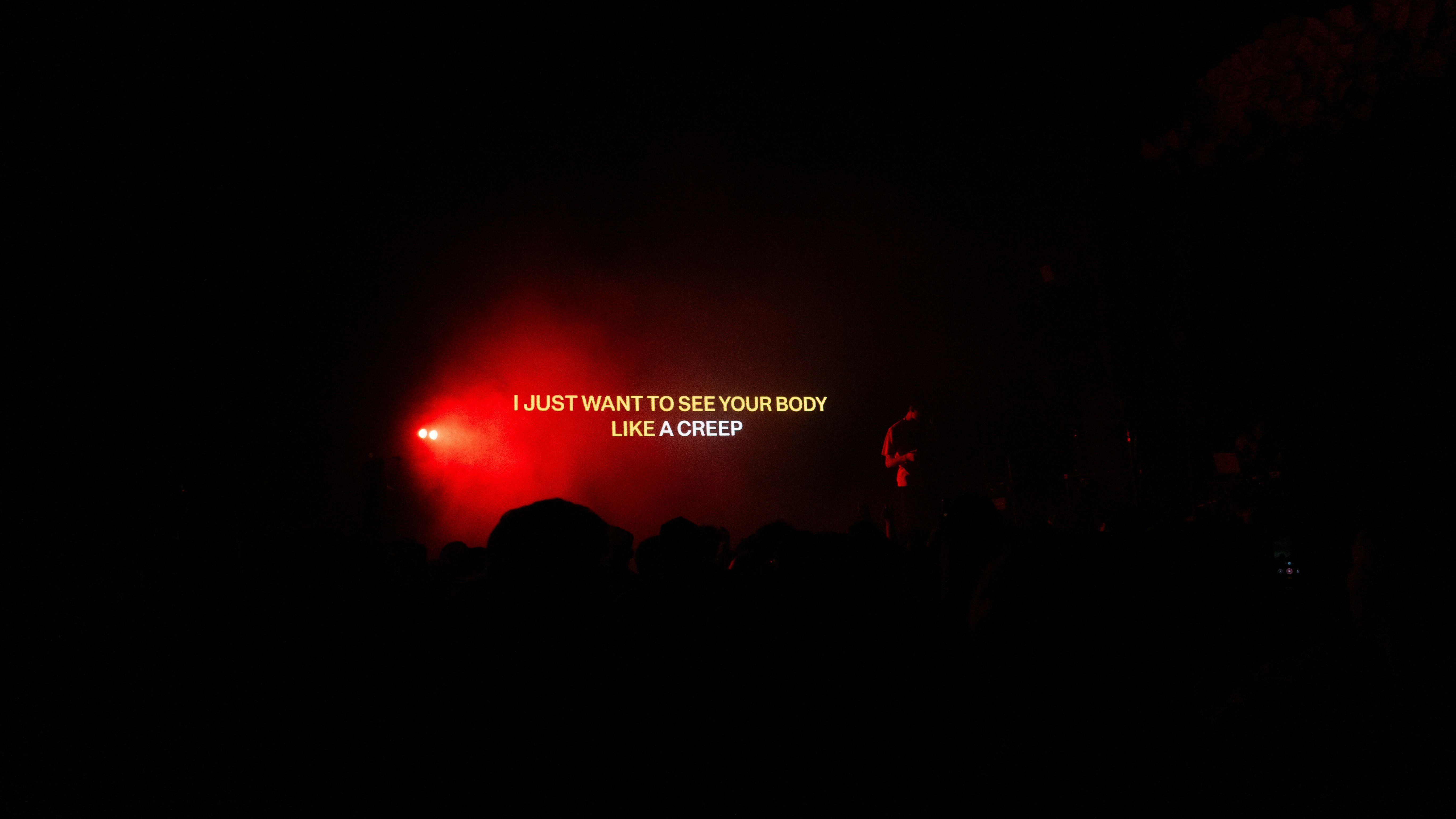 Red spotlight illuminates text on a dark stage.