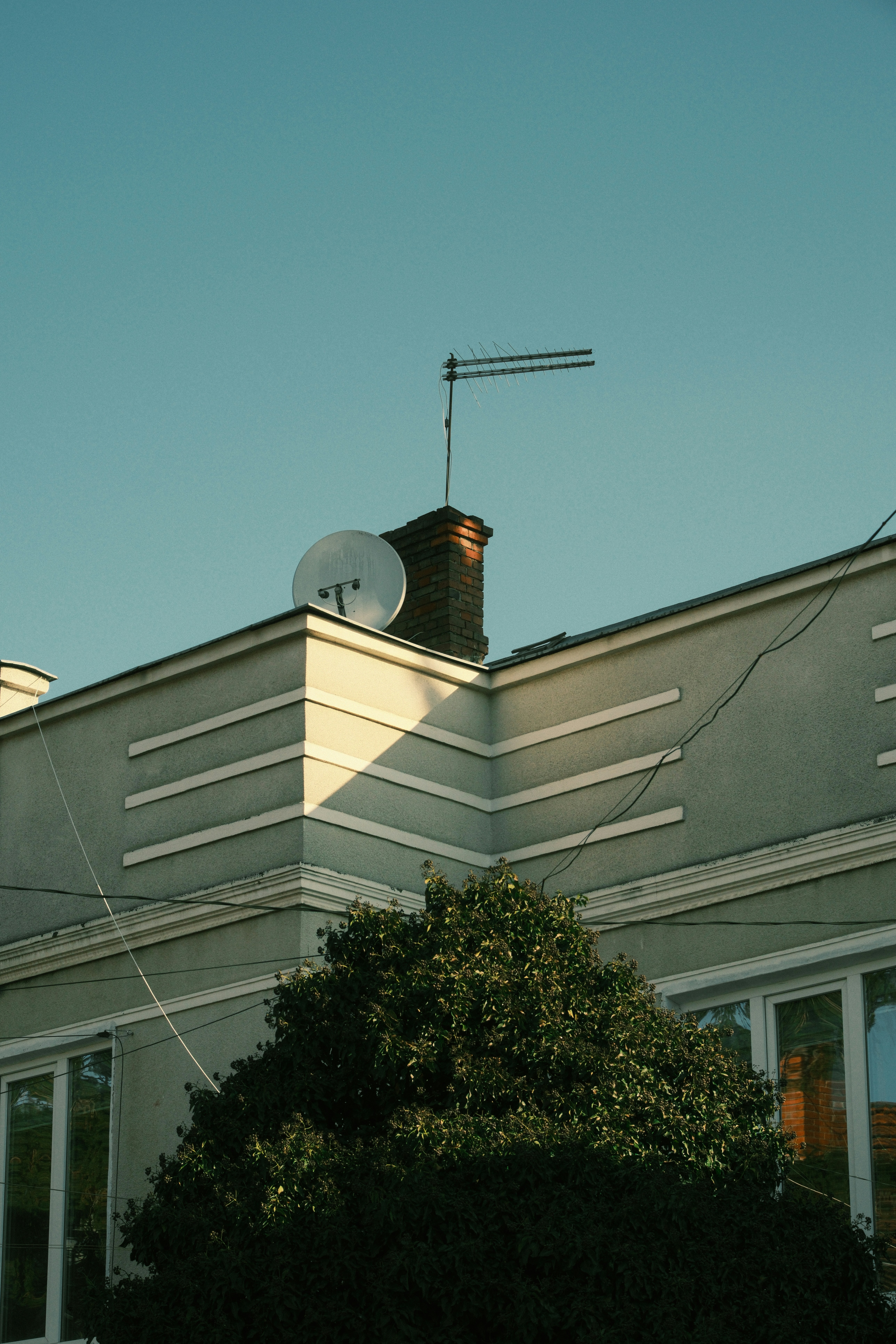 Rooftop with satellite dish and antenna under clear blue sky