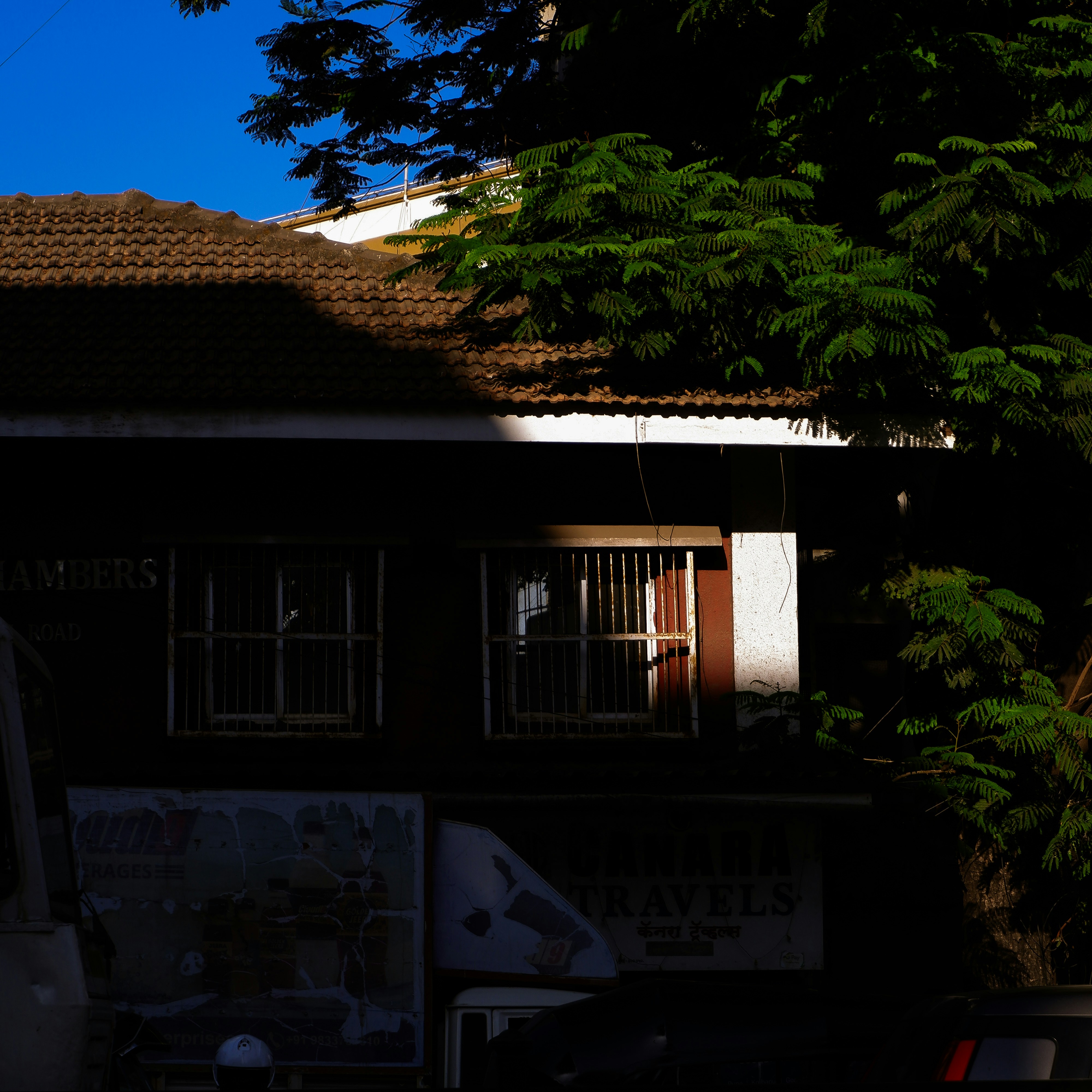 Darkened building facade with windows and trees