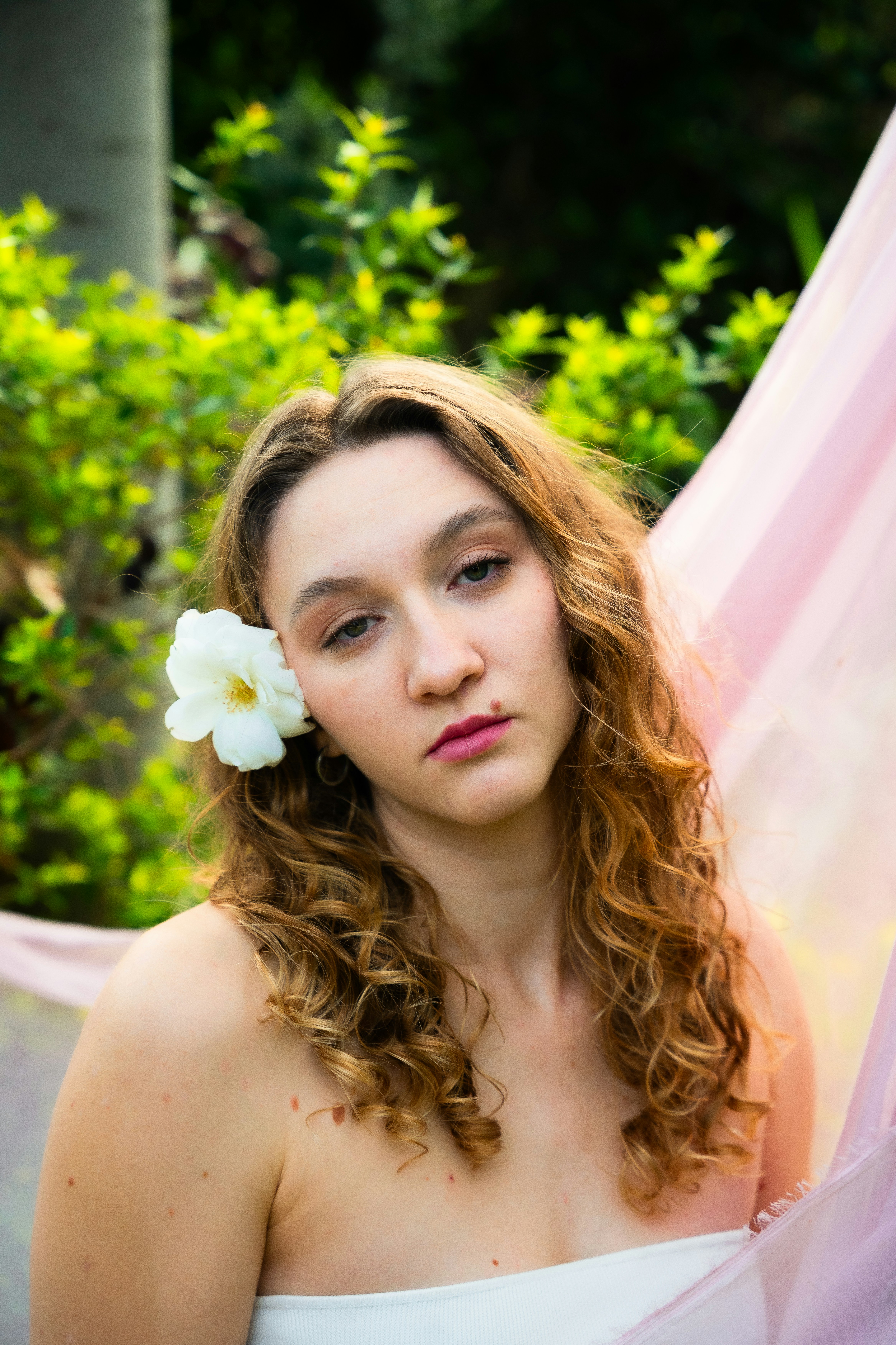 Wanita muda dengan bunga di rambutnya di luar ruangan