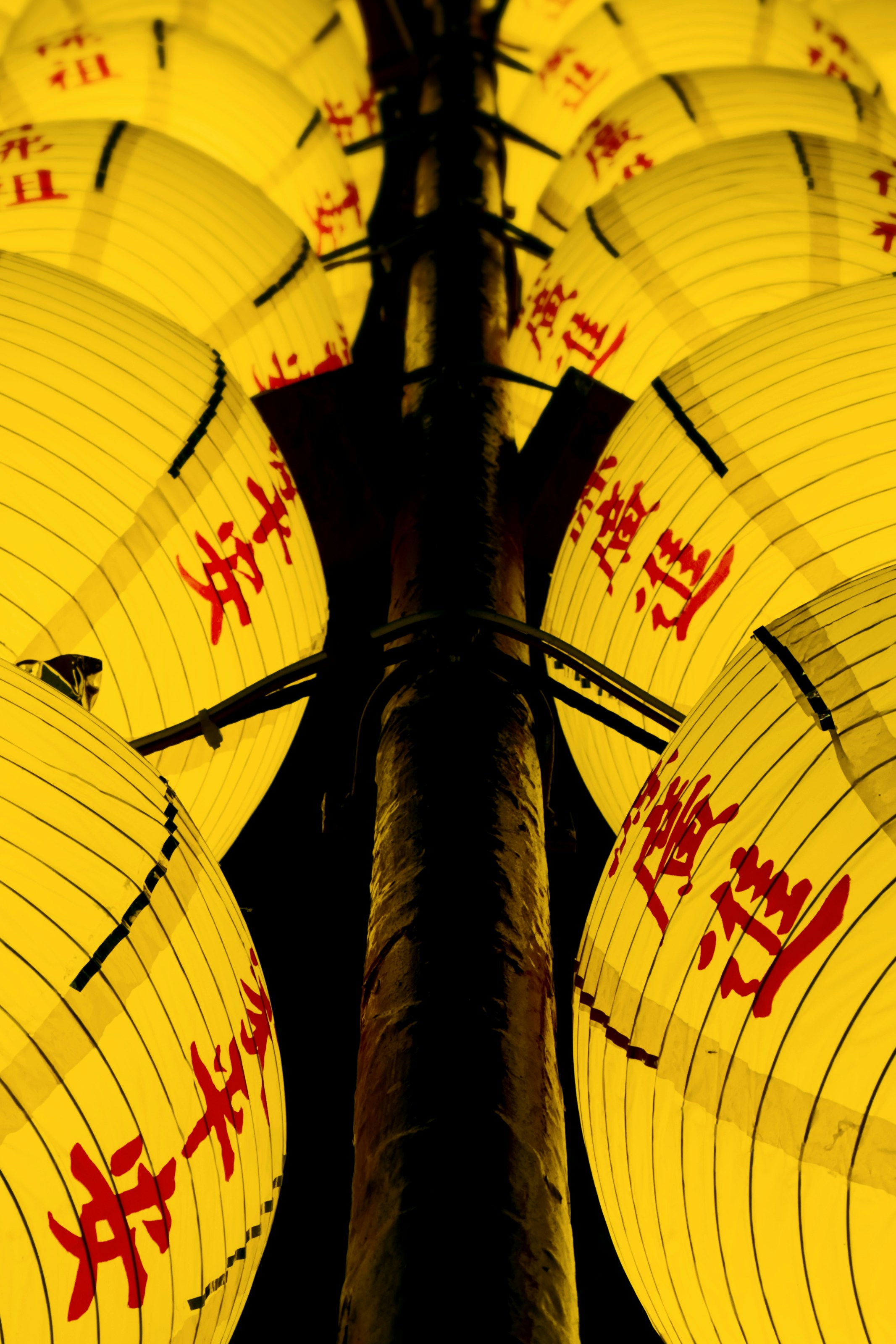 Bright yellow lanterns with red chinese characters hang from pole
