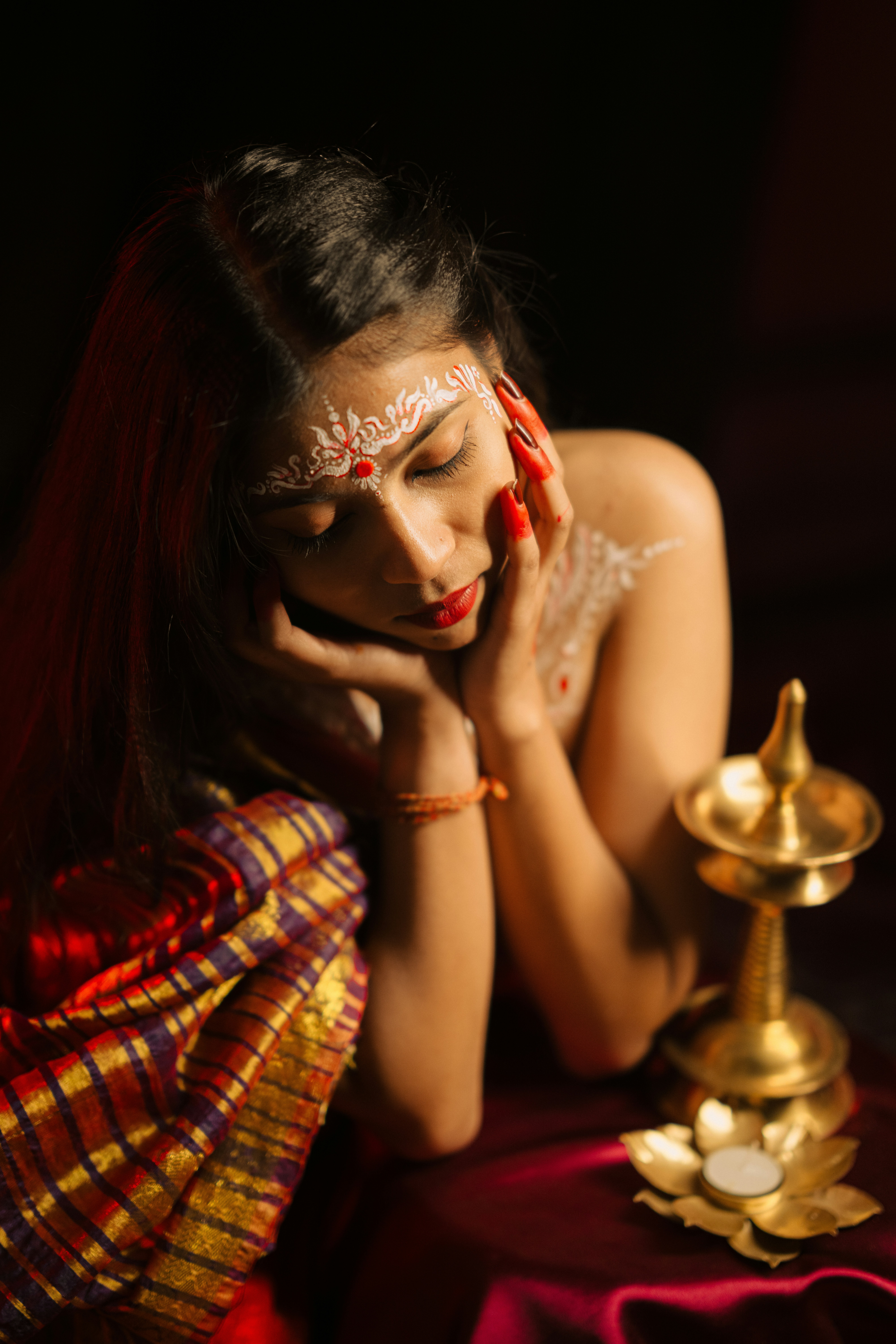 Young woman with traditional markings and a brass oil lamp.