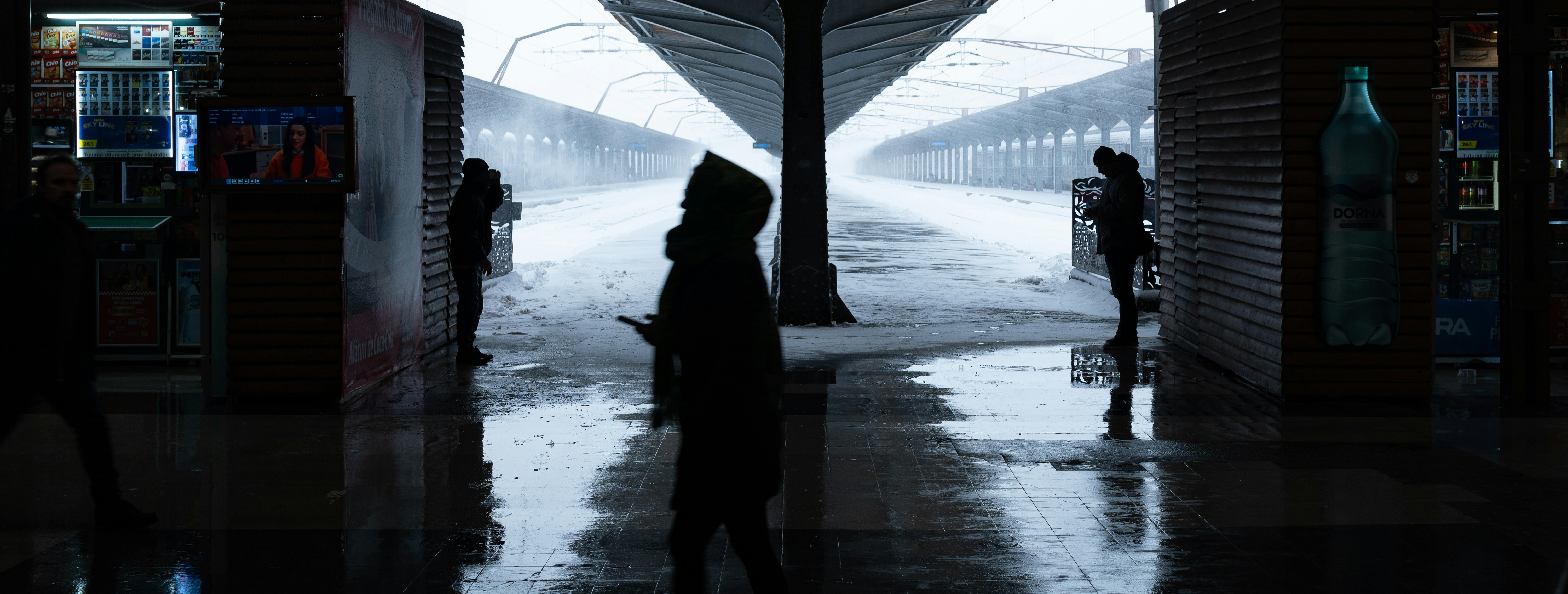 Silhouettes of people in a rainy, urban setting.