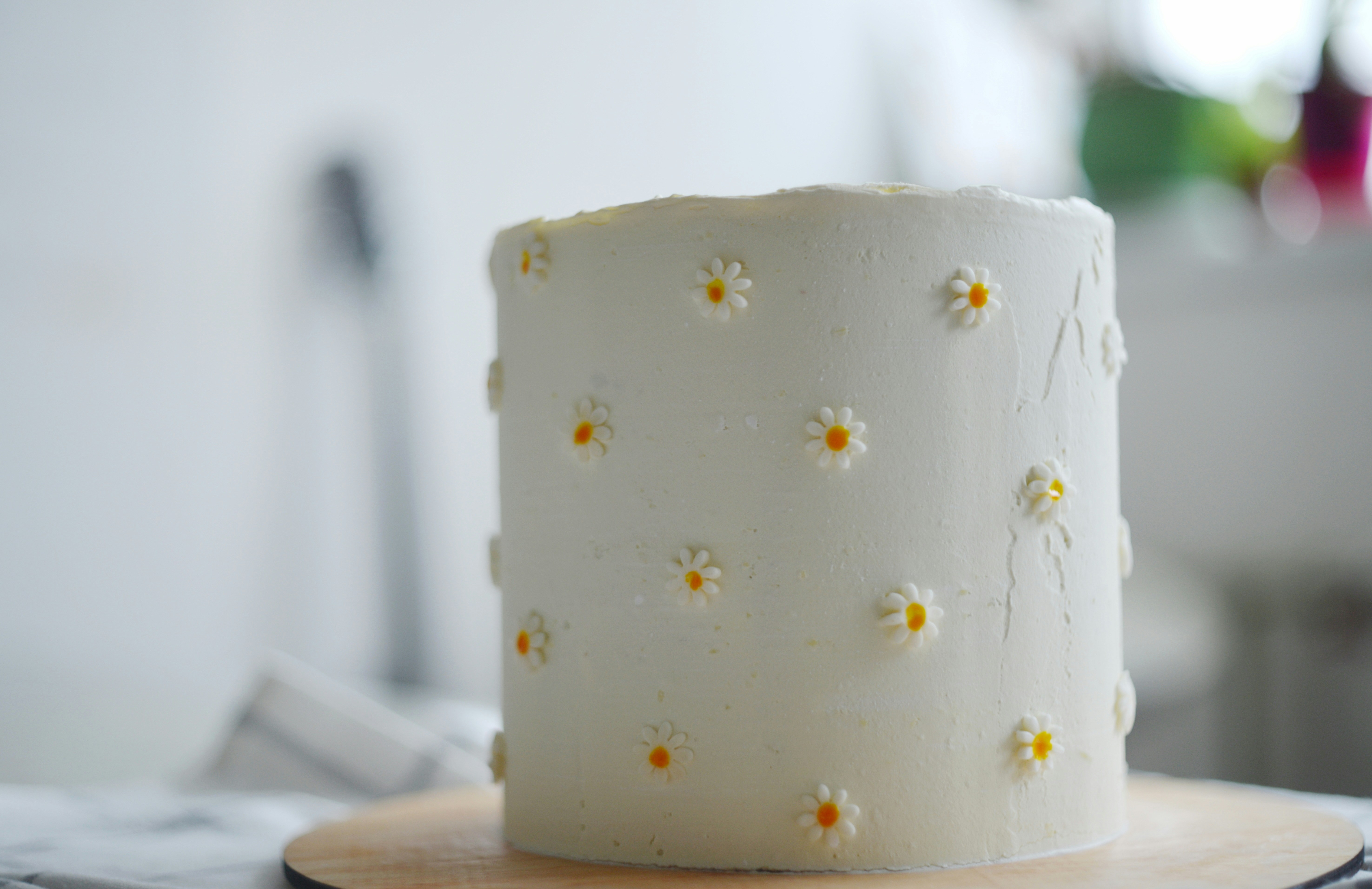 A white cake decorated with small daisy flowers