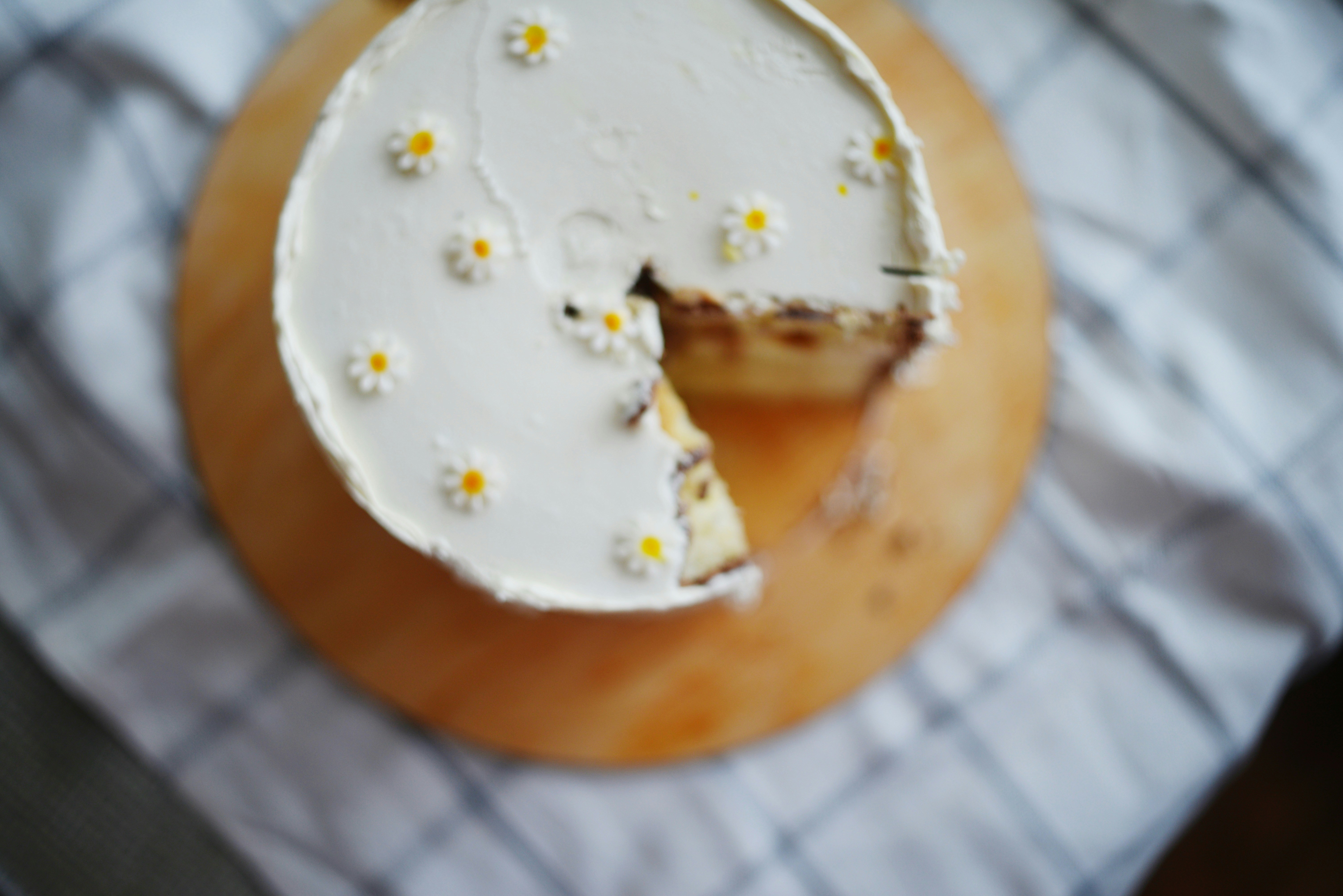 Un pastel blanco decorado con pequeñas flores de margarita.