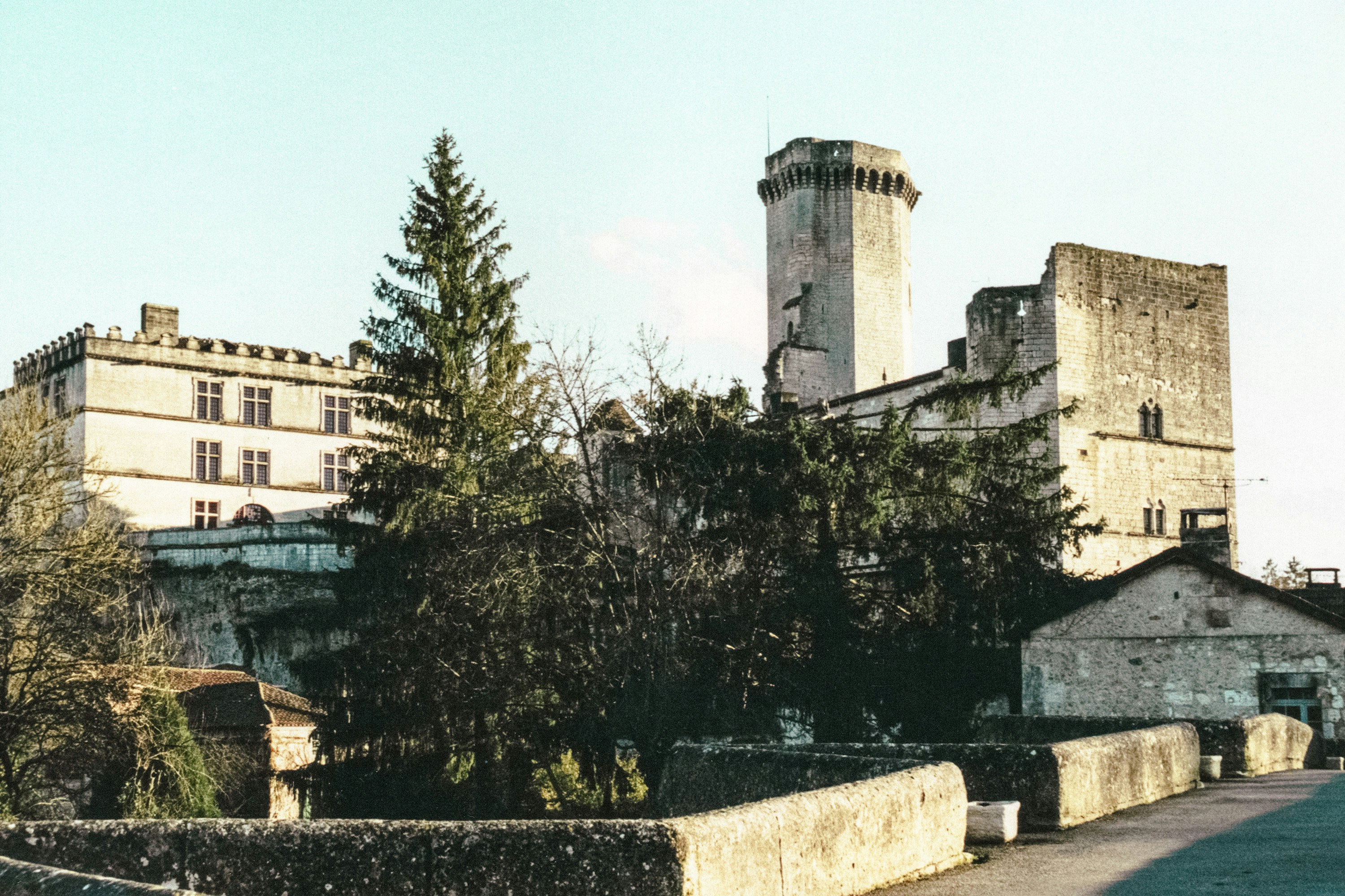 Ancient stone castle with tall tower and surrounding trees.