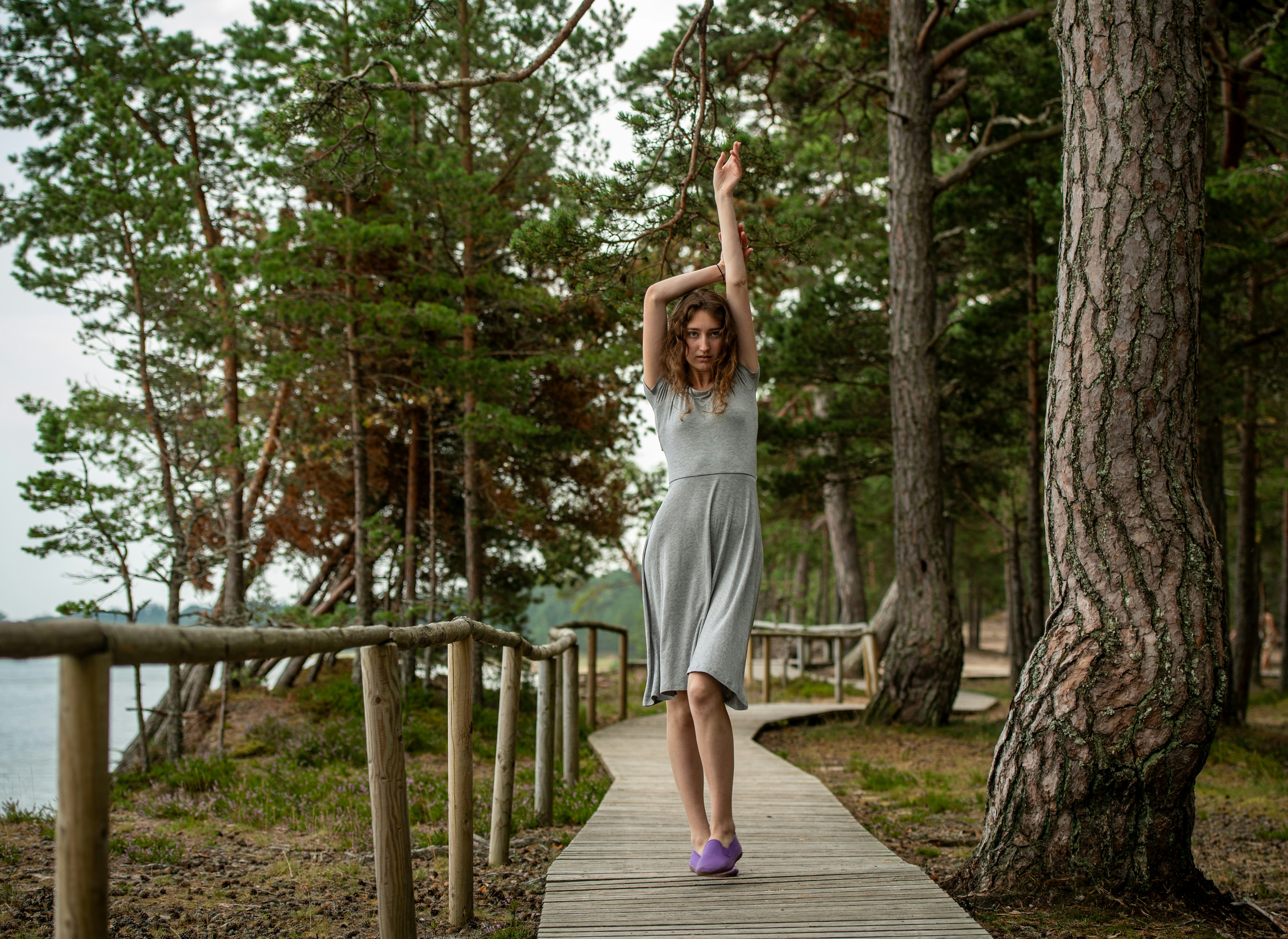 Woman in grey dress walks on boardwalk in forest 풍경 사진