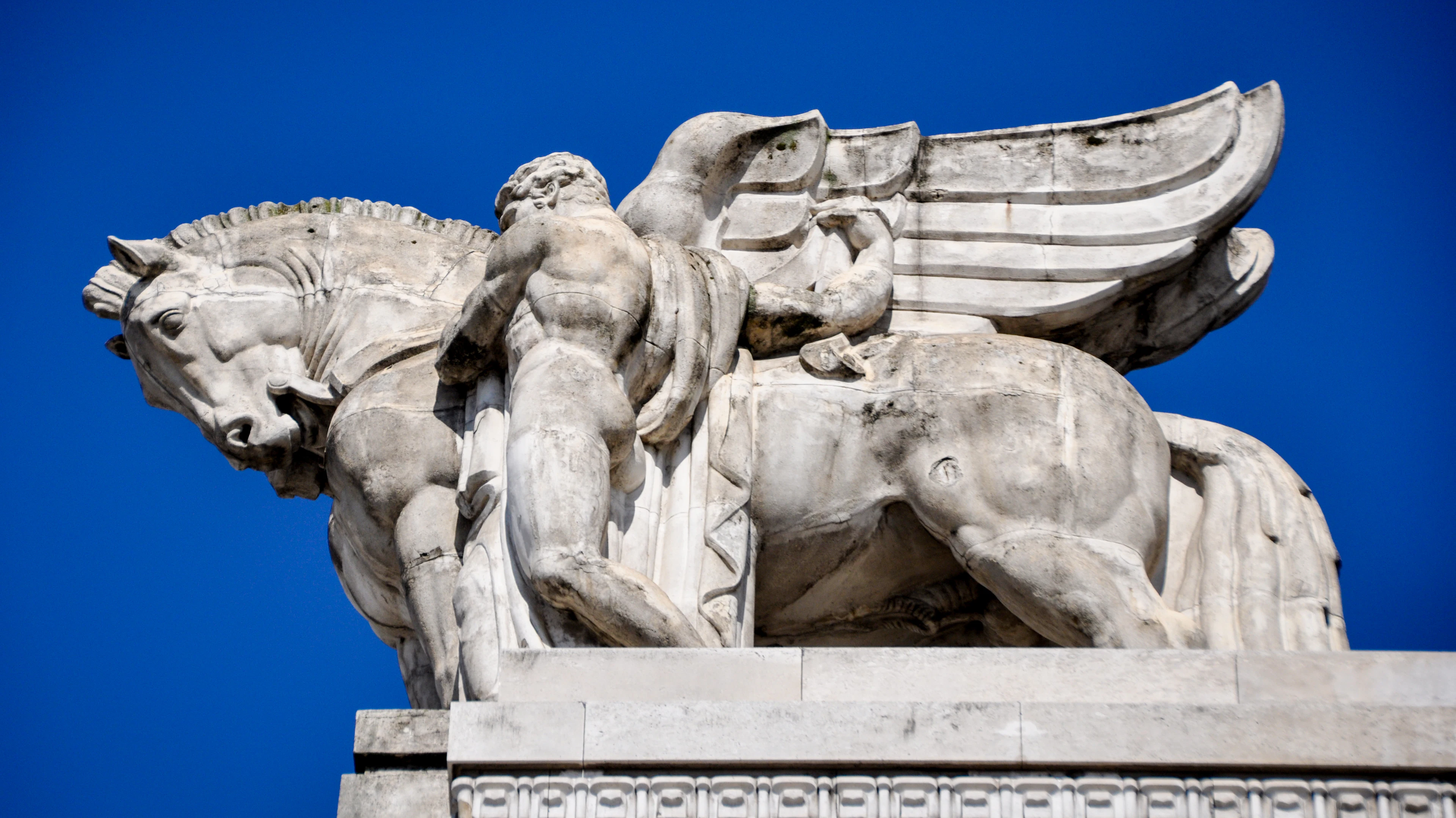 A stone sculpture of a winged horse and a man on the roof of Milan's Central railway station