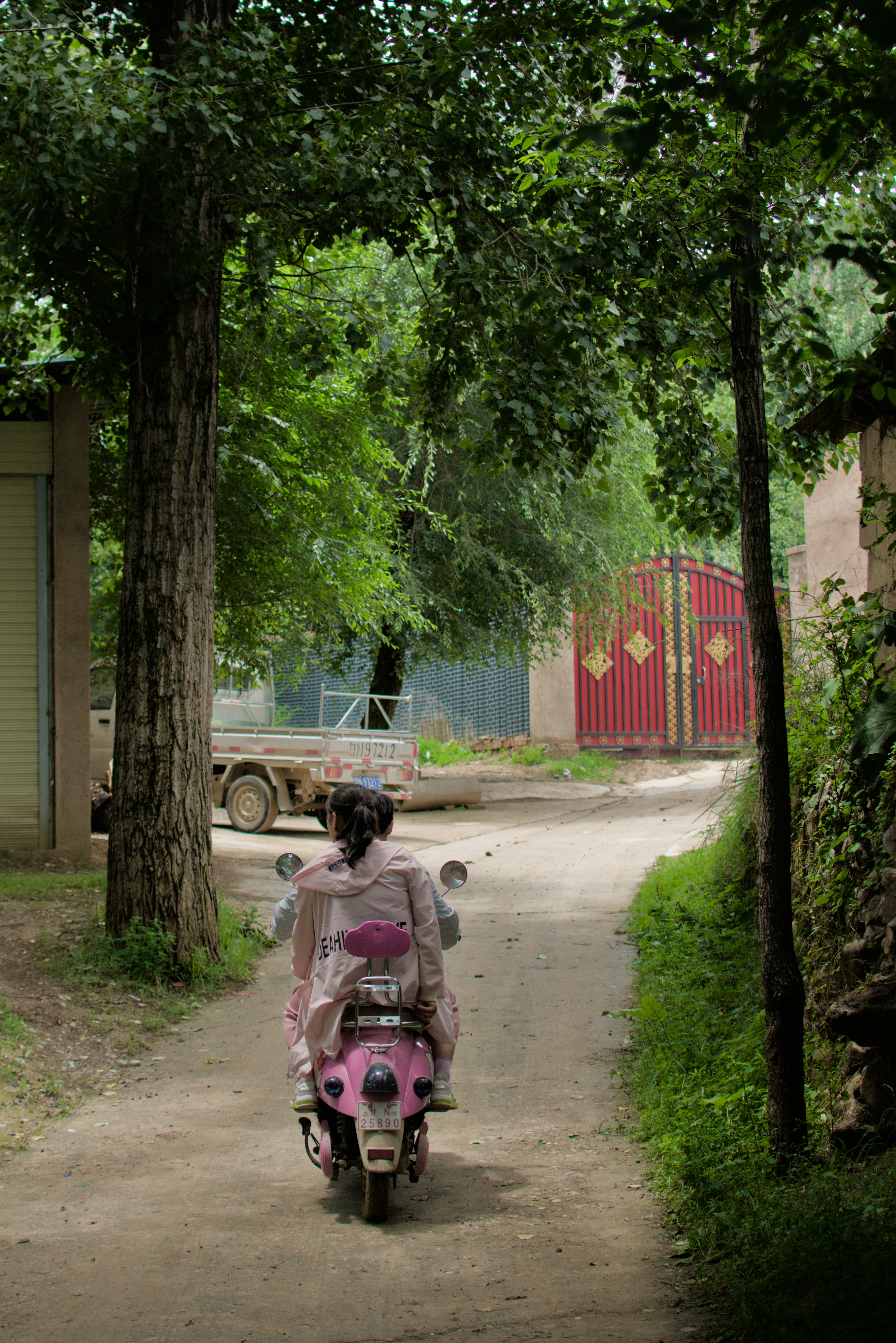 Woman riding pink scooter down dirt road