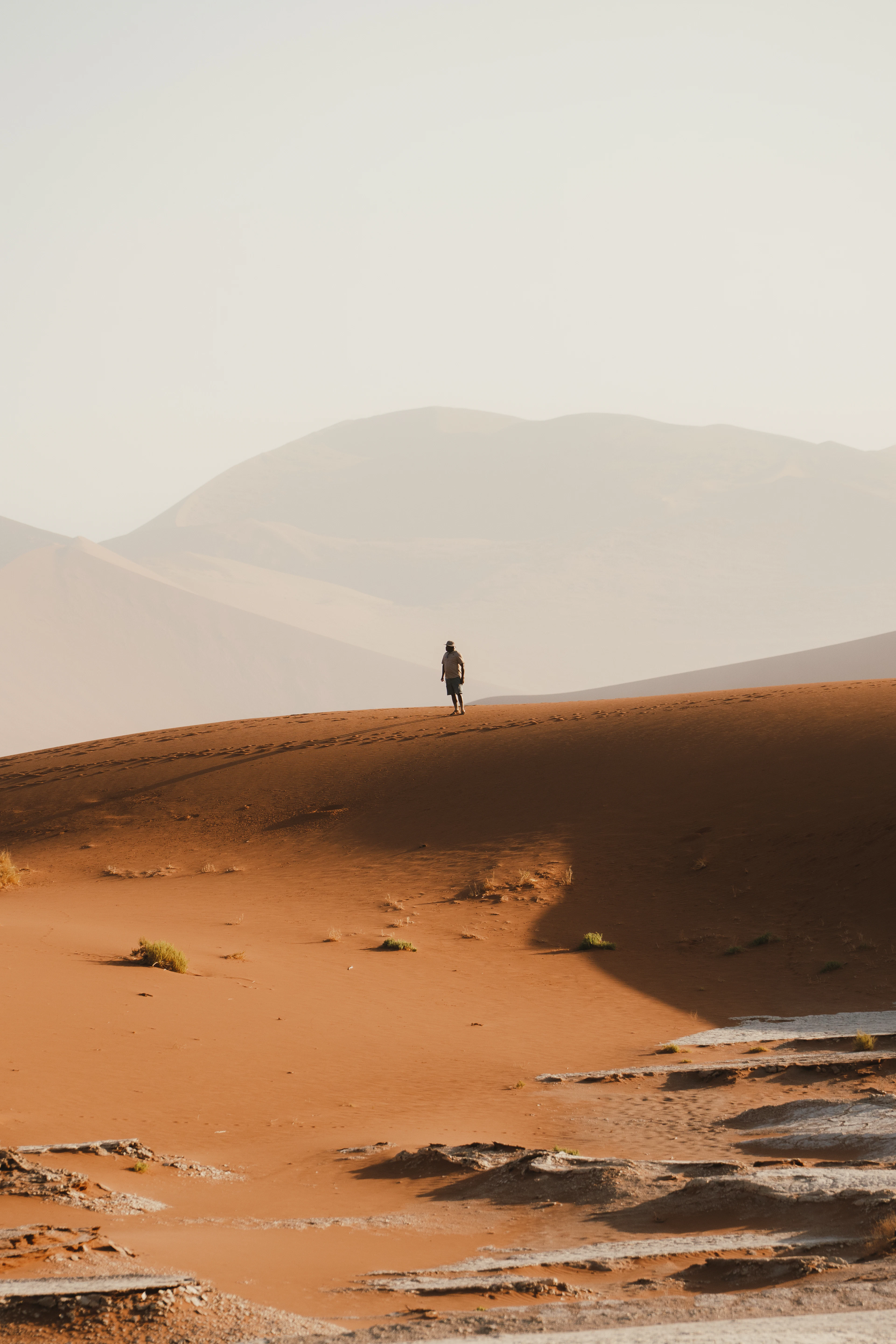 A lone walker crossing a red sand dune in Sossusvlei, Namibia