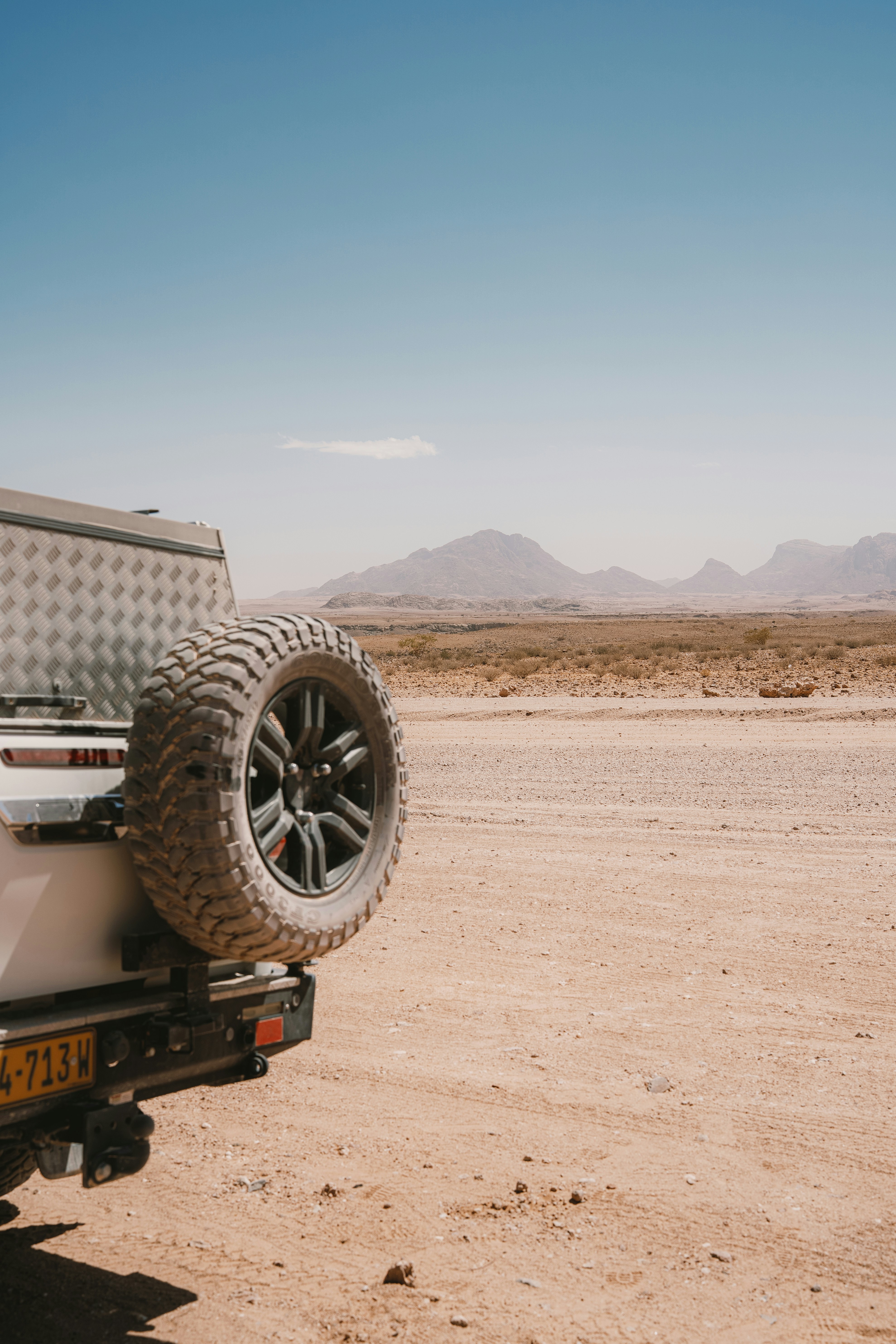 Off-road vehicle parked in a dry, dusty desert landscape.