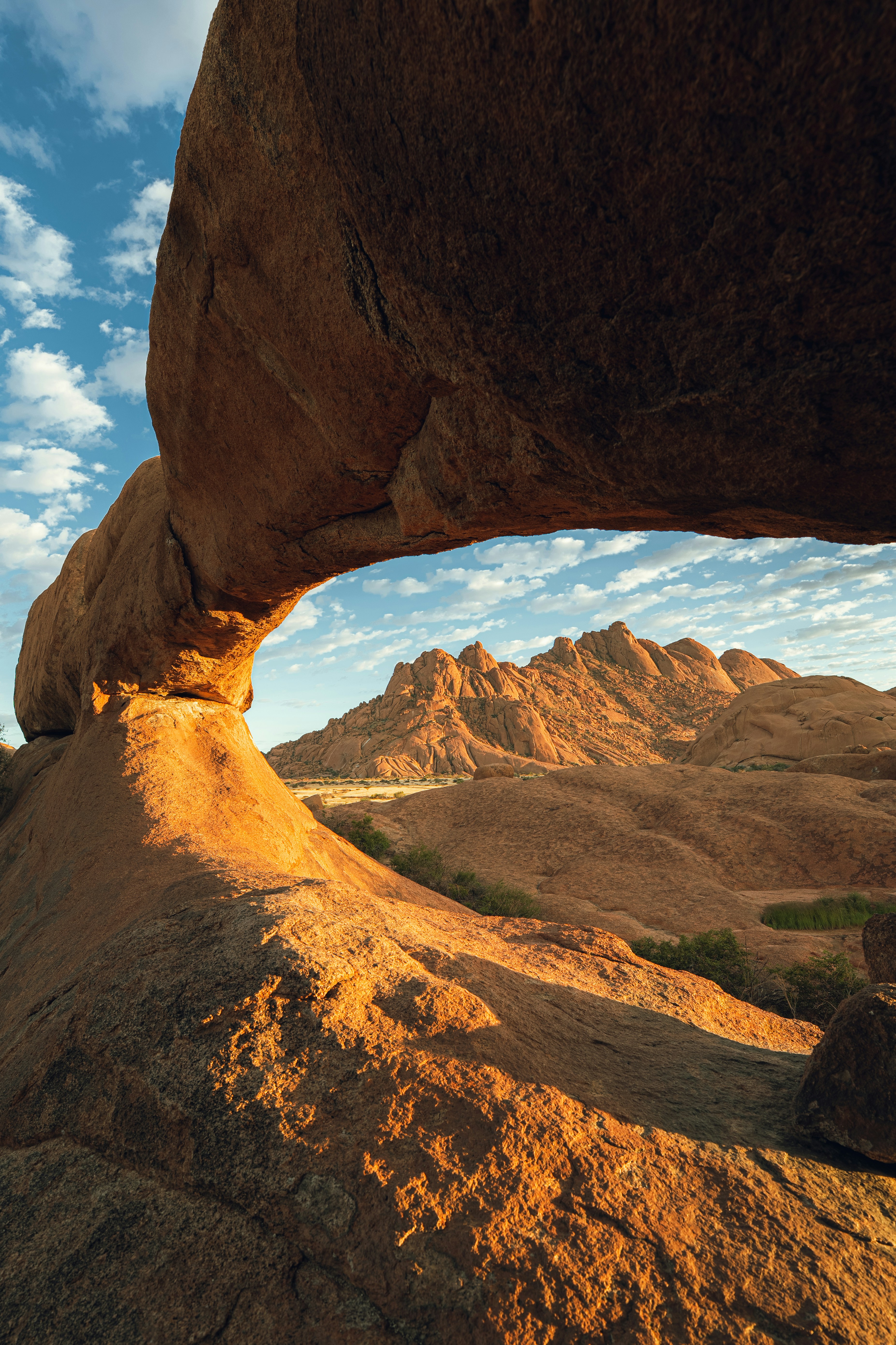 Rock arch framing desert mountains under a blue sky