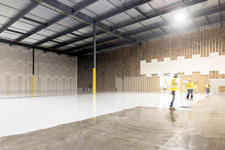 Two construction workers in a large empty warehouse
