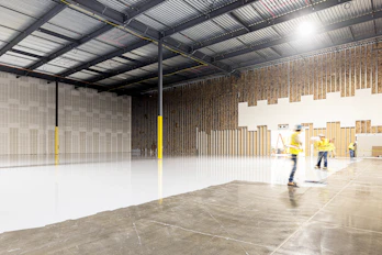 Two construction workers in a large empty warehouse