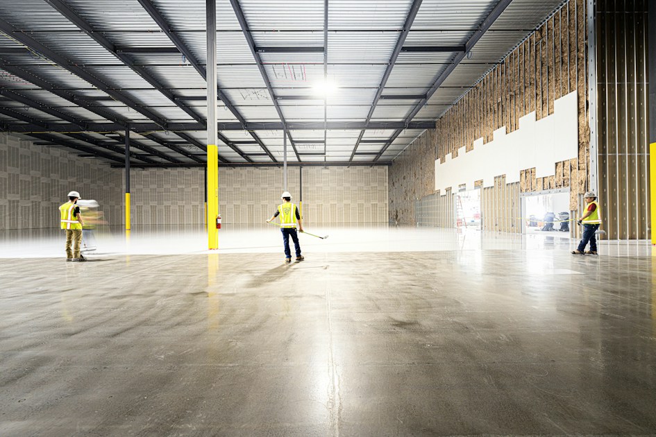 Workers inspecting a large empty industrial warehouse space