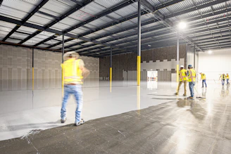 Workers in a large, empty warehouse with polished floors.