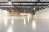 Spacious empty warehouse interior with polished concrete floor.