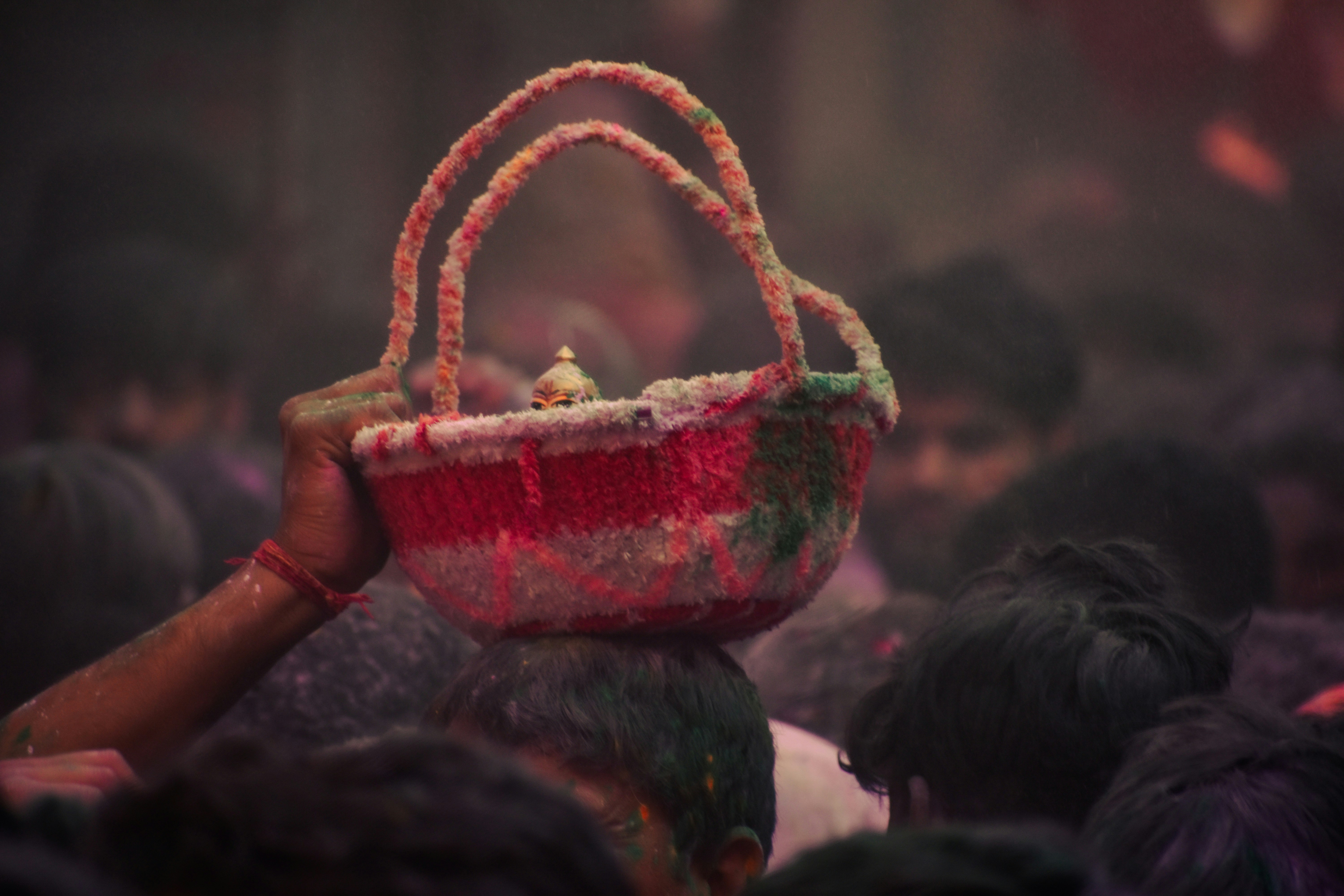 A person holds a colorful basket above a crowd.