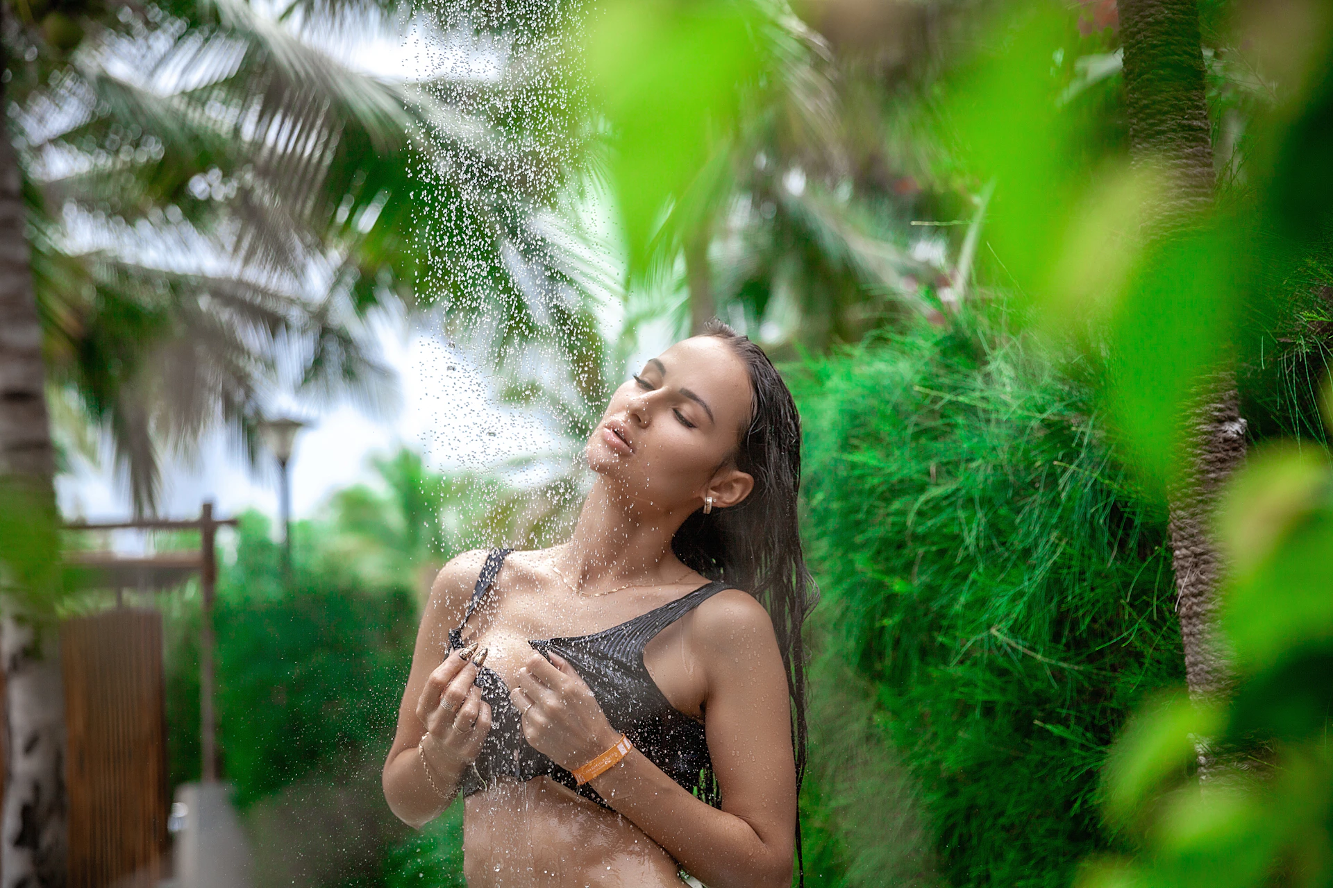Woman showering outdoors surrounded by lush greenery