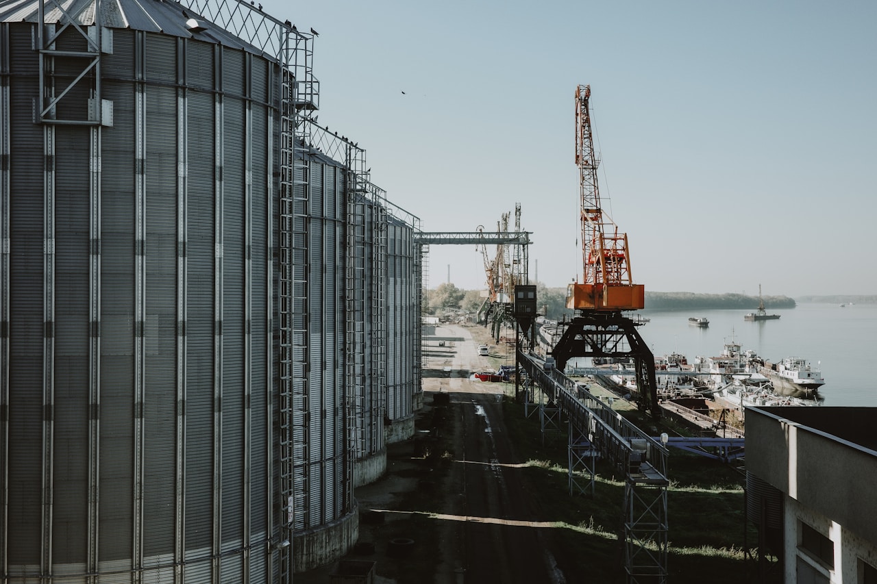 A Black Sea-style grain port with industrial silos and loading cranes at the dock — illustrating why the Black Sea corridor functions not as an alternative to Hormuz but as a parallel insurance line for Türkiye during the 80-day shock
