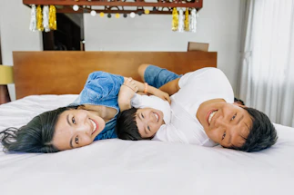 A happy family lying on a bed together.
